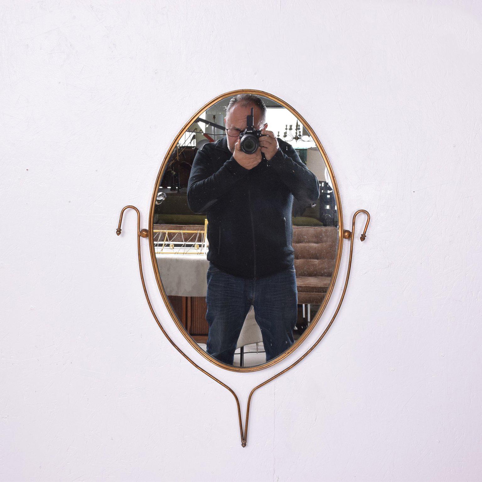 For your consideration a vintage wall mirror in oval shape with a sculptural accent. 

It includes a new mirror. The brass has the original vintage patina and can be polished and sealed upon request. 

Unmarked, Italy, circa 1950s. 

 
The