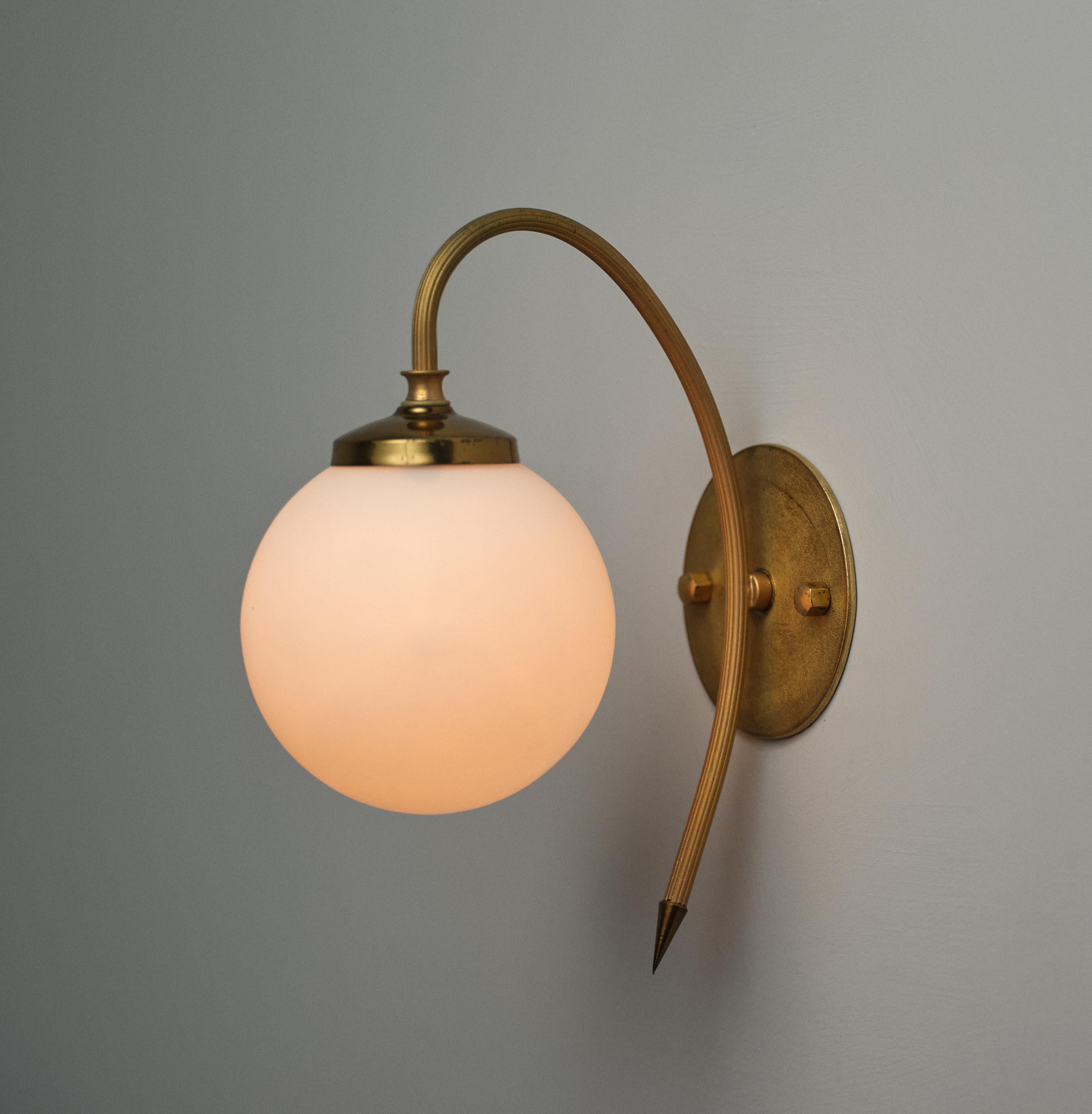 L'applique murale illustre le design italien des années 1950, avec une esthétique épurée et élégante. La lampe est fabriquée en laiton et présente une patine bien entretenue qui ajoute du caractère à la surface du métal. L'applique est équipée d'un
