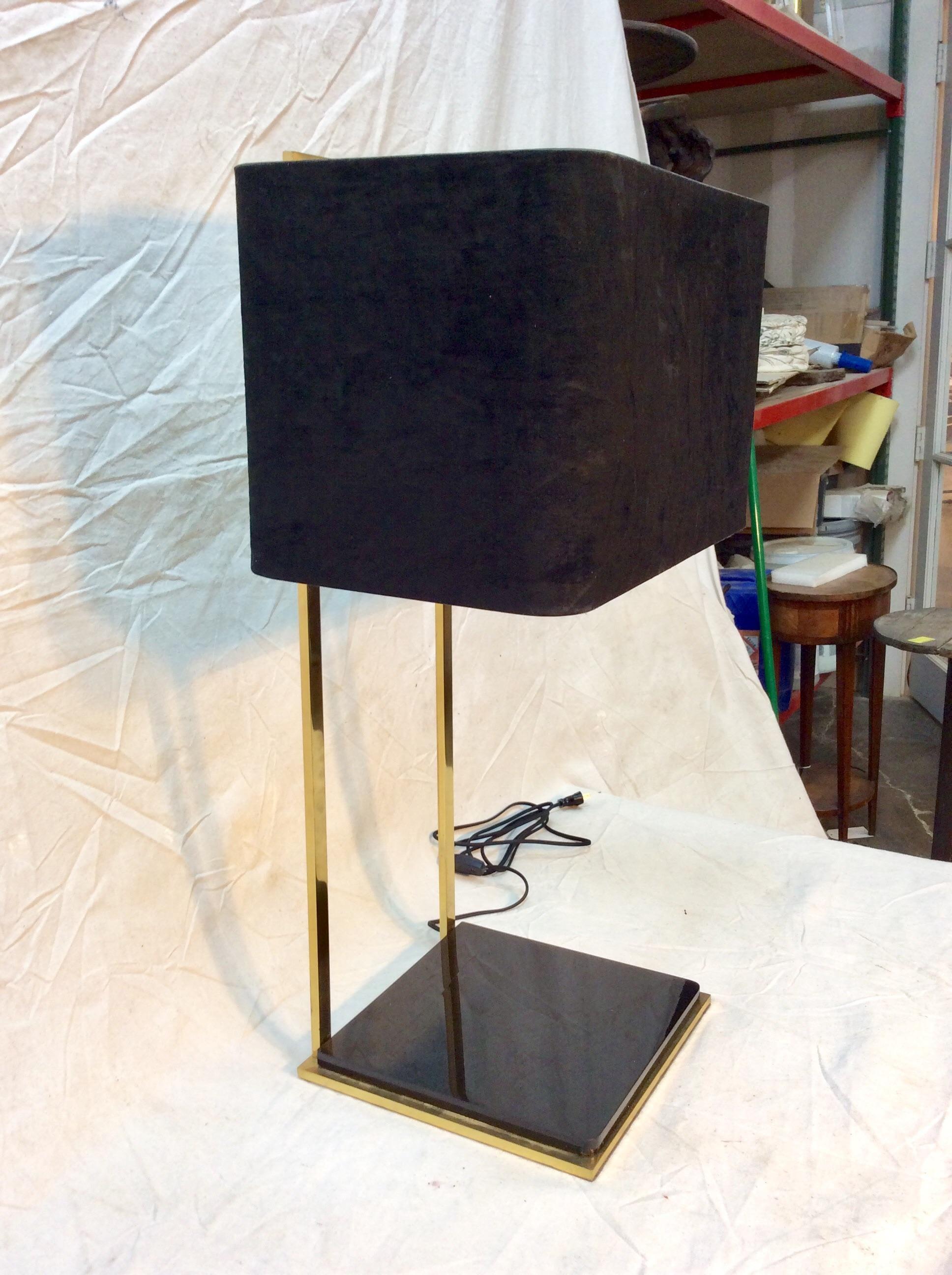 This Mid Century Modern Italian Brass Table Lamp features brass construction with a black acrylic base. The black shade with its gold interior is secured to the lamp socket in the style of an Uno Fitter. Designed in a clean-lined fashion, this piece
