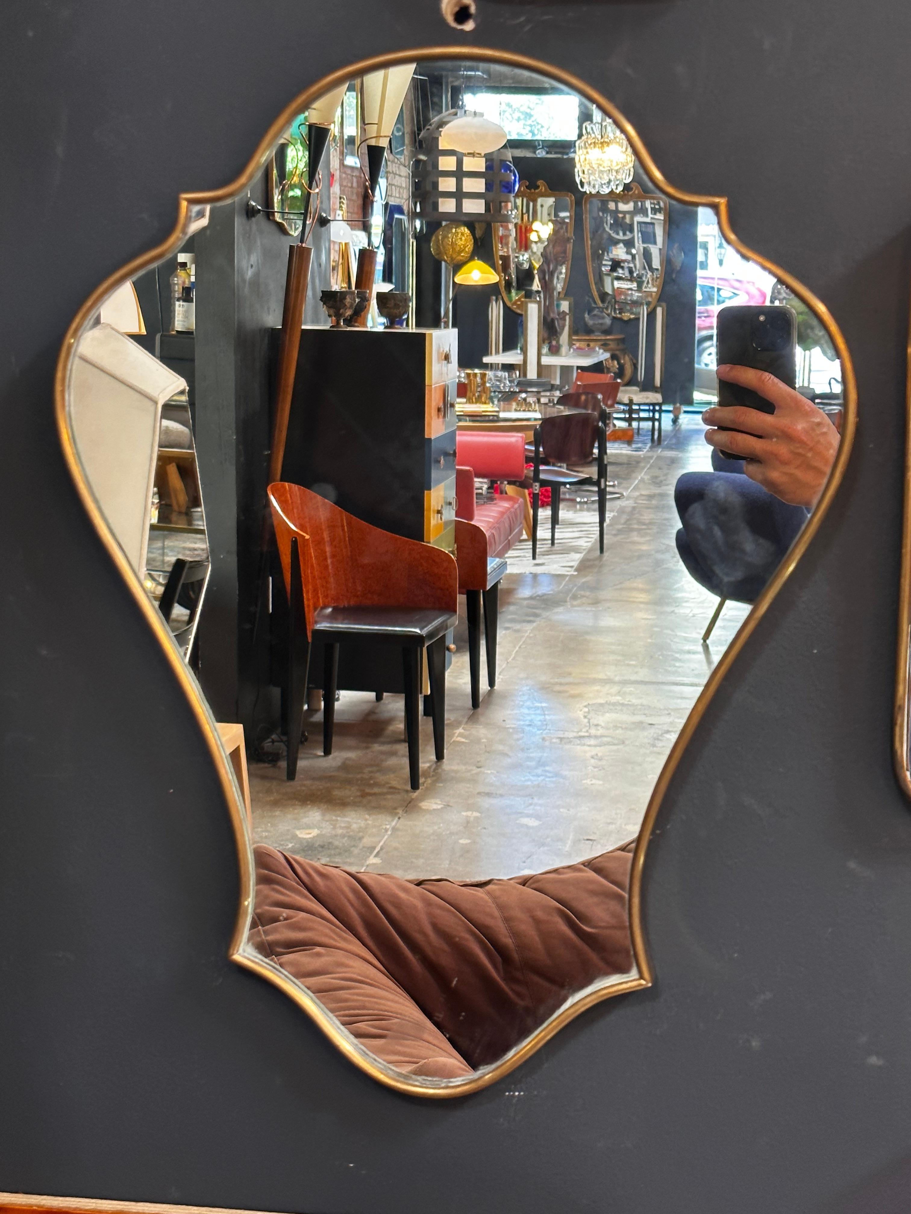 Exemplifying the mid-century modern aesthetic, this Italian brass wall mirror from the 1960s captures the essence of sleek design. Its clean lines and brass elements harmonize to create a piece that embodies the style of its era.

