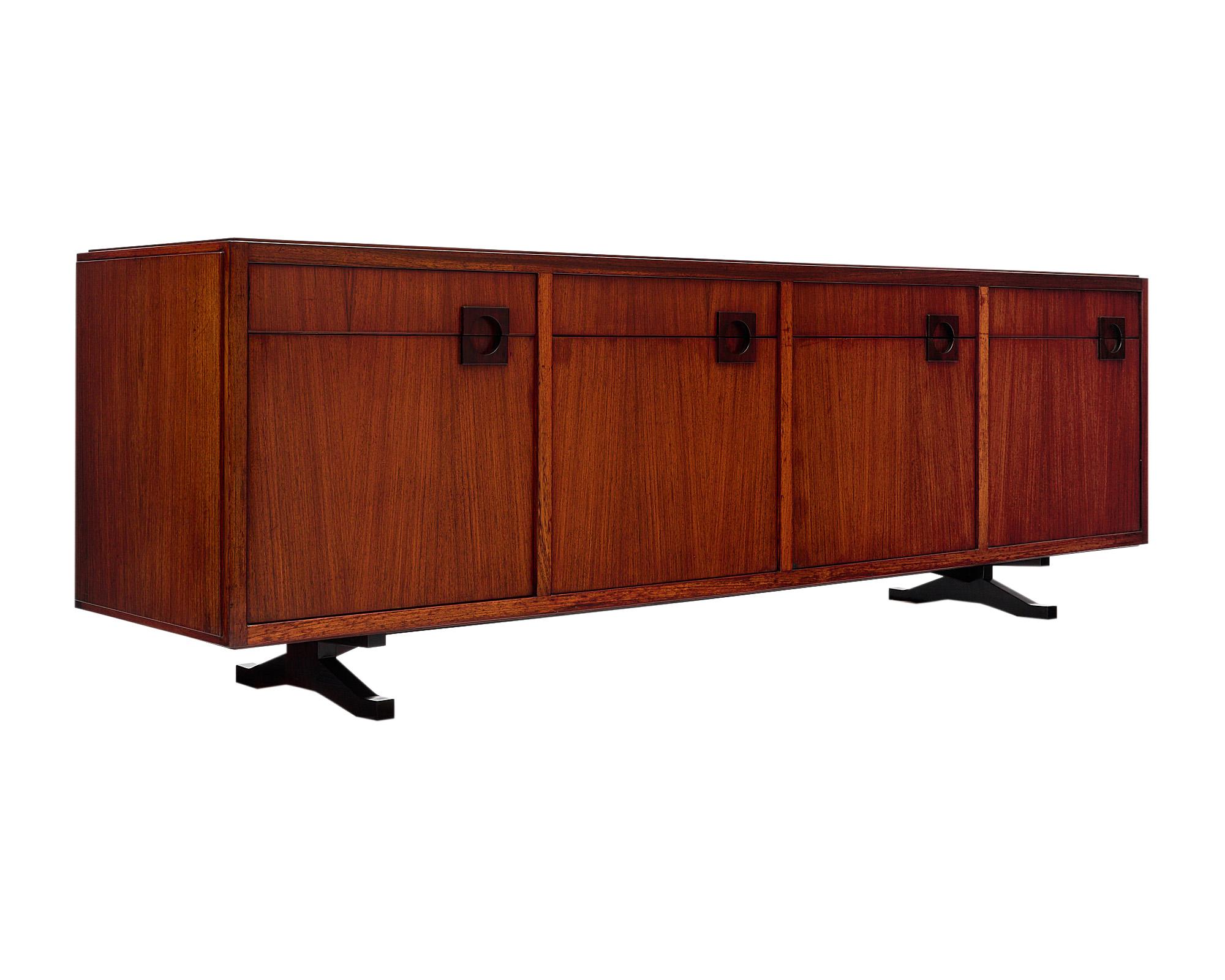 Mid century modern Italian buffet/credenza made of solid Brazilian rosewood rio. This strongly built Italian sideboard; crafted in the region of Milan; features four doors opening to ample storage and four dovetailed drawers. It is designed by