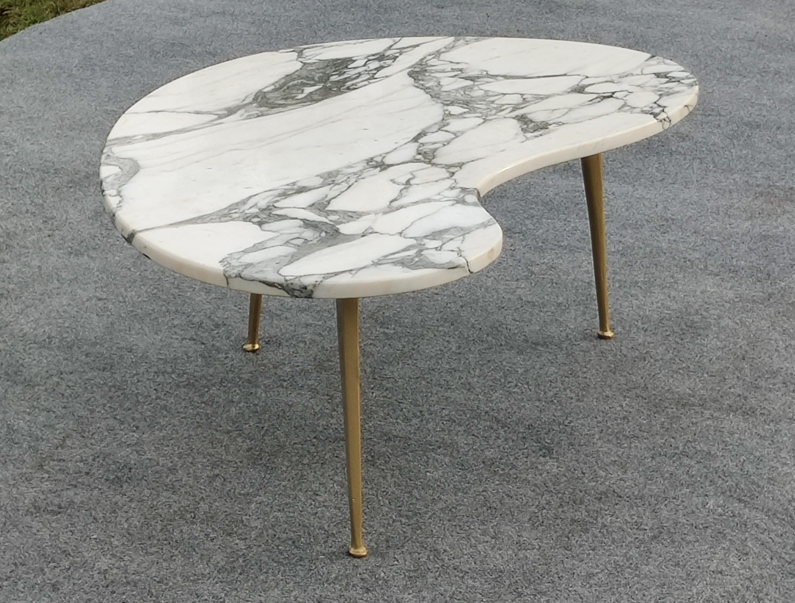 Conçue d'après les travaux de Gio Ponti ou d'Ico Parisi, cette merveilleuse table basse présente un plateau en marbre Calacatta, taillé en une forme de rein courbe et séduisante. Le marbre blanc veiné de noir, associé à des pieds en laiton, confère