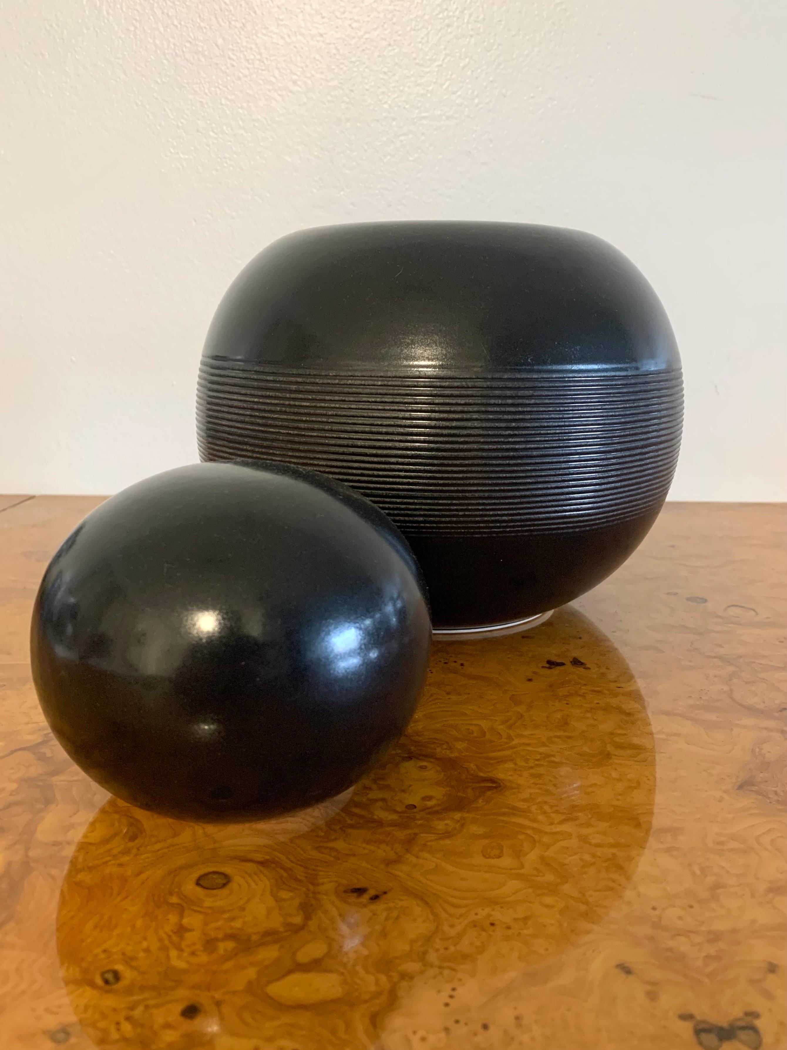 A beautiful deep black studio ceramic lidded vessel made in Italy by Franco Bucci. Has an elegant simple spherical form with a tasteful textured base. A smaller sphere creating the lid. Made in the 1950s-1960s. 

Measuring 8” wide by 10.5” tall.