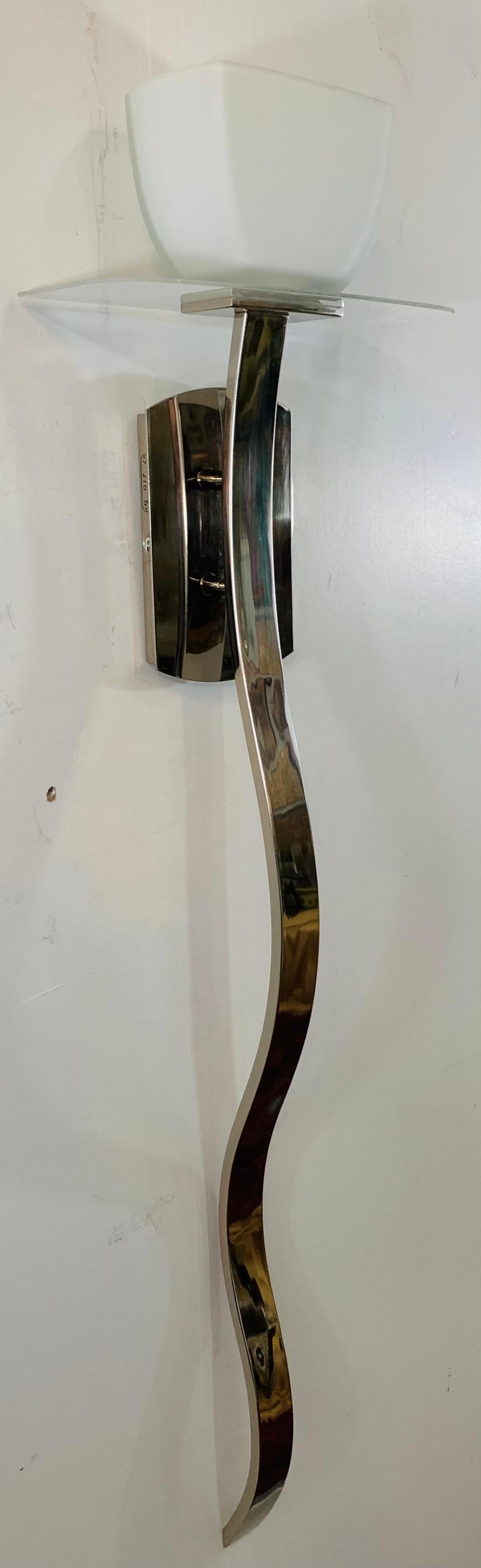 A very stylish Mid-Century Modern pair of Italian chrome wall sconces. The sconces contemporary Cobra wavy design is highly attractive adding character to the pieces. The wall sconces also features beautiful opaline shades.

Dimensions: 44
