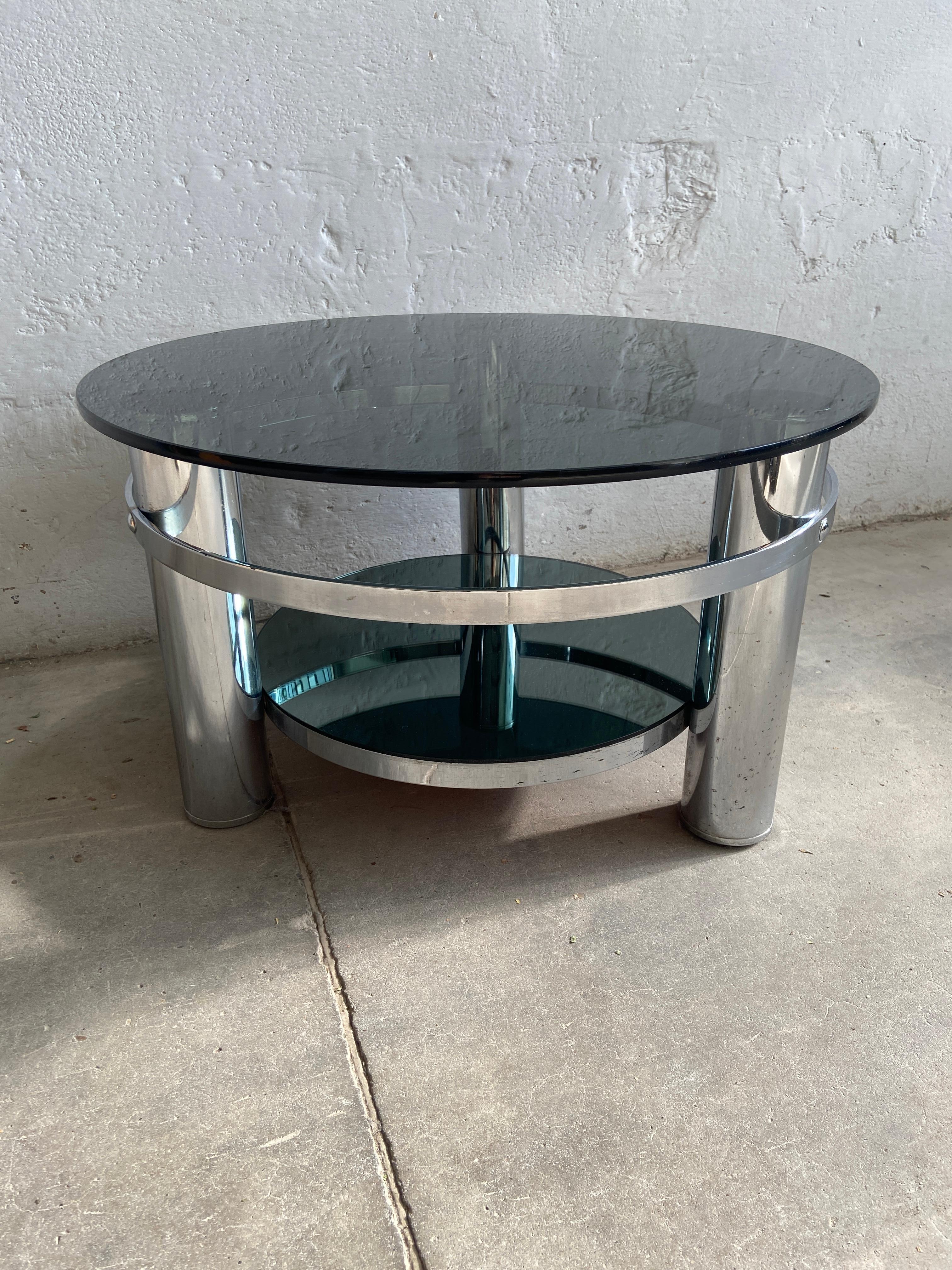 Mid-Century Modern Italian round chrome coffee table with smoked glass top and mirrored low level shelf.
The smoked glass top presents a little scratch but overall the table is in really good vintage condition.