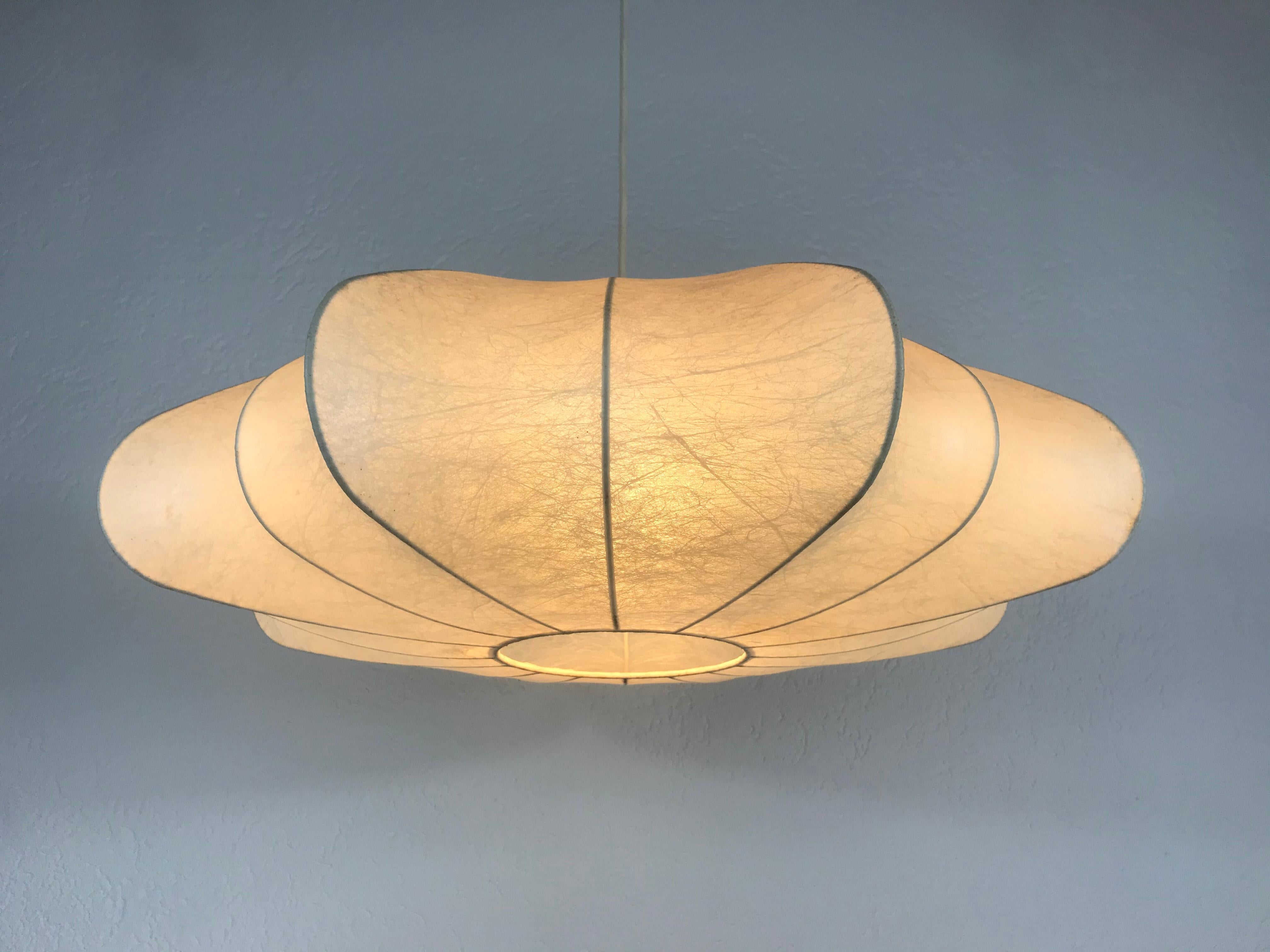 Eine Hängelampe in Kokonform, hergestellt in Italien in den 1960er Jahren. Sie hat ein schönes asymmetrisches Design, das an die Lampen von Castiglioni erinnert. 

Höhe des Schirms: 20 cm

Gesamthöhe: 65 cm

Die Leuchte benötigt eine