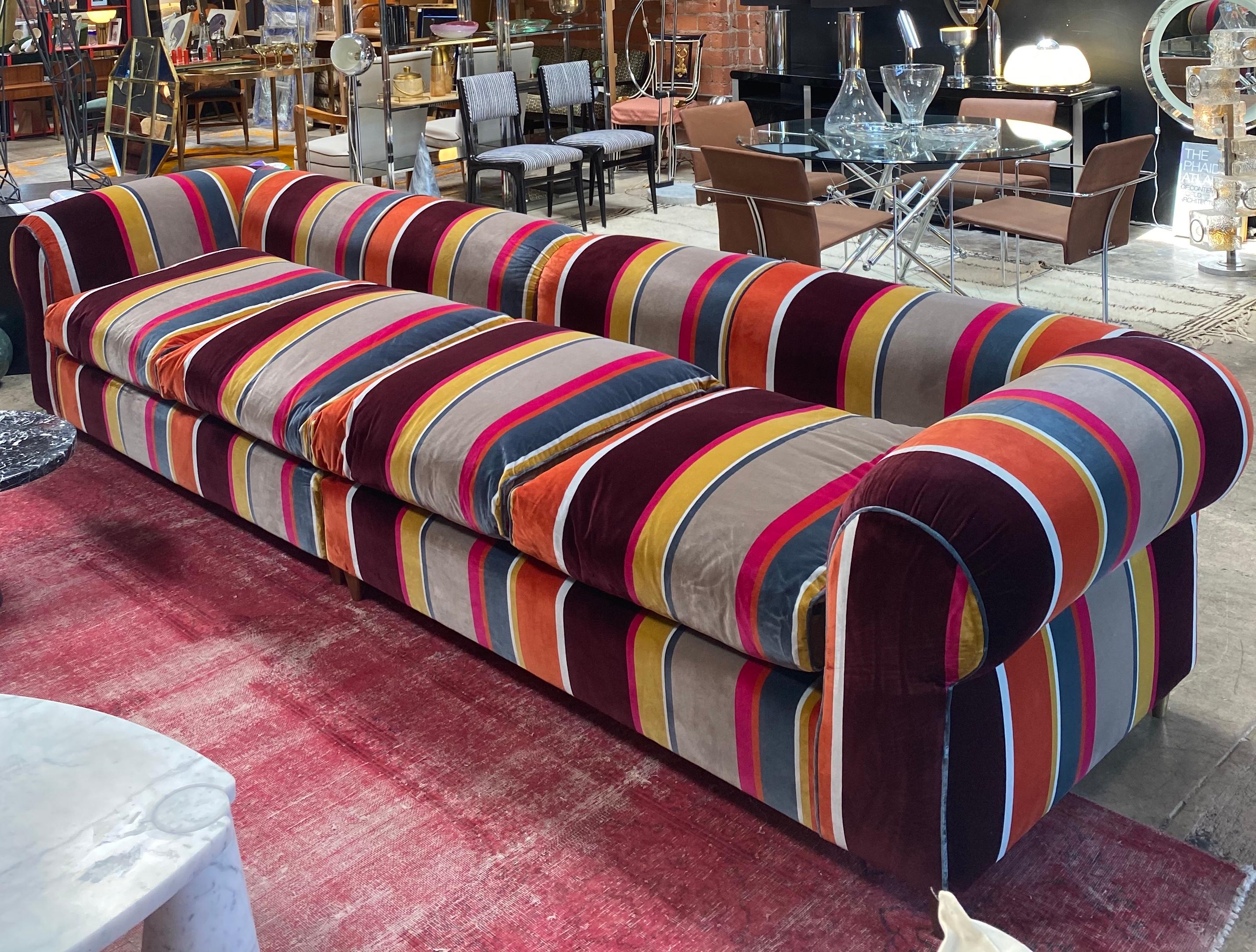 Reupholstered with a original printed velvet fabric whose colorful and abstract pattern evokes the lively charm of the 1980s, this stunning sofa boasts a unique silhouette to match any decor.