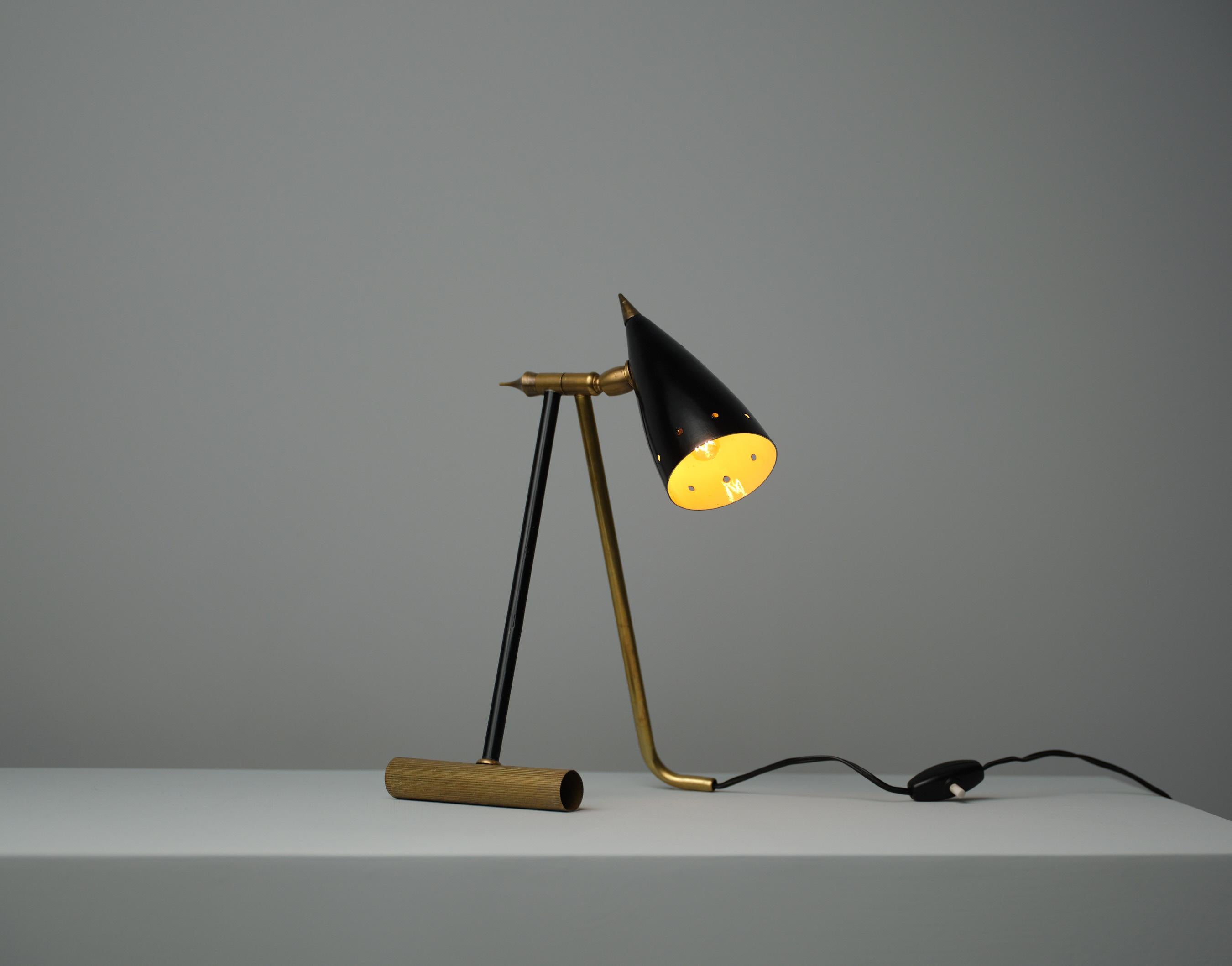 Cette lampe de table illustre le design italien des années 1950, mettant l'accent à la fois sur la forme esthétique et l'utilité. Construite en laiton et en métal laqué noir, la lampe est dotée d'un bras articulé et d'un abat-jour conique qui peut
