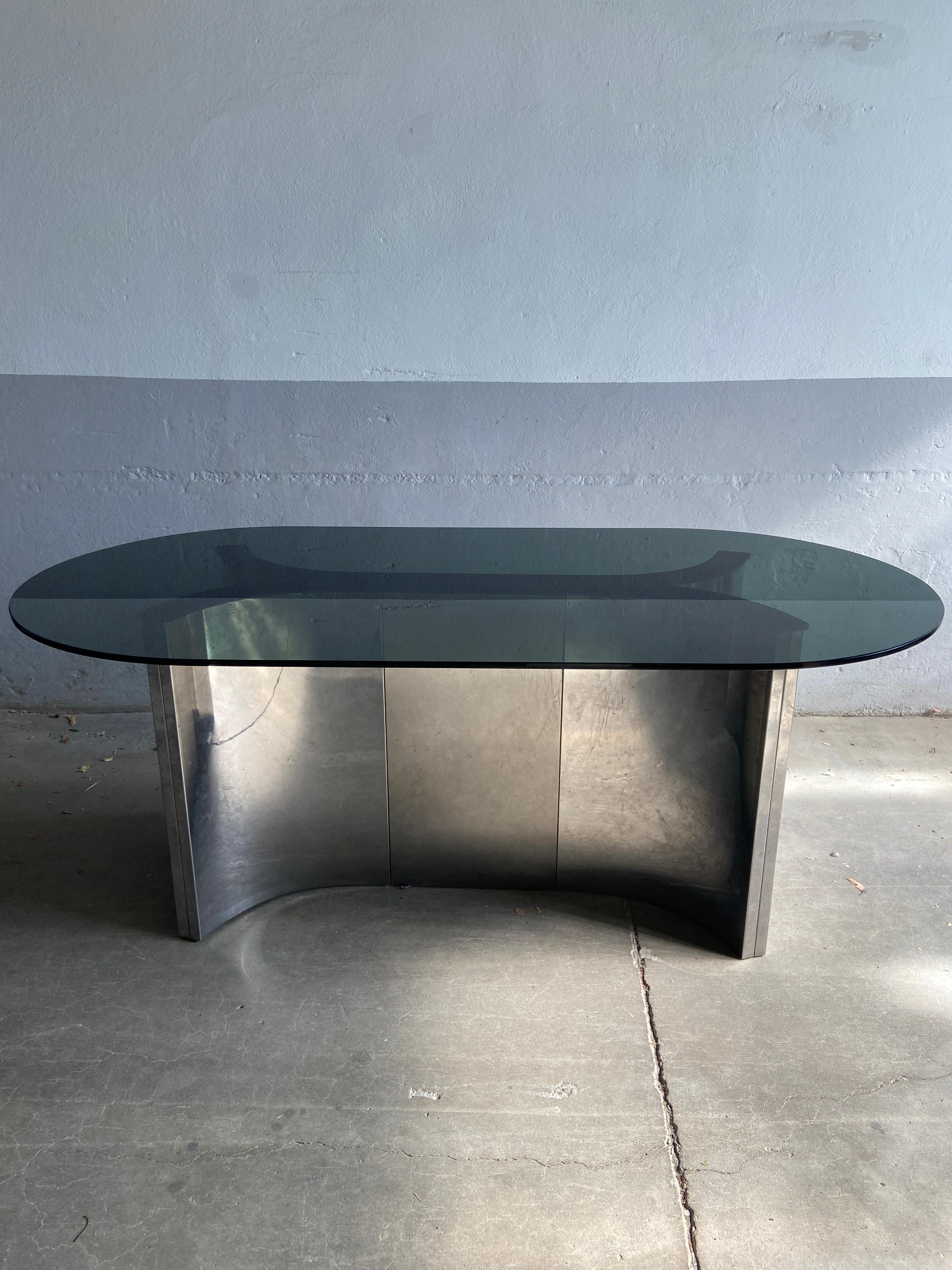 Mid-Century Modern Italian dining or conference stainless steel table with oval smoked glass top from 1970s.
The glass top presents a couple of signs due to age and use, but the table results in very good vintage conditions.
