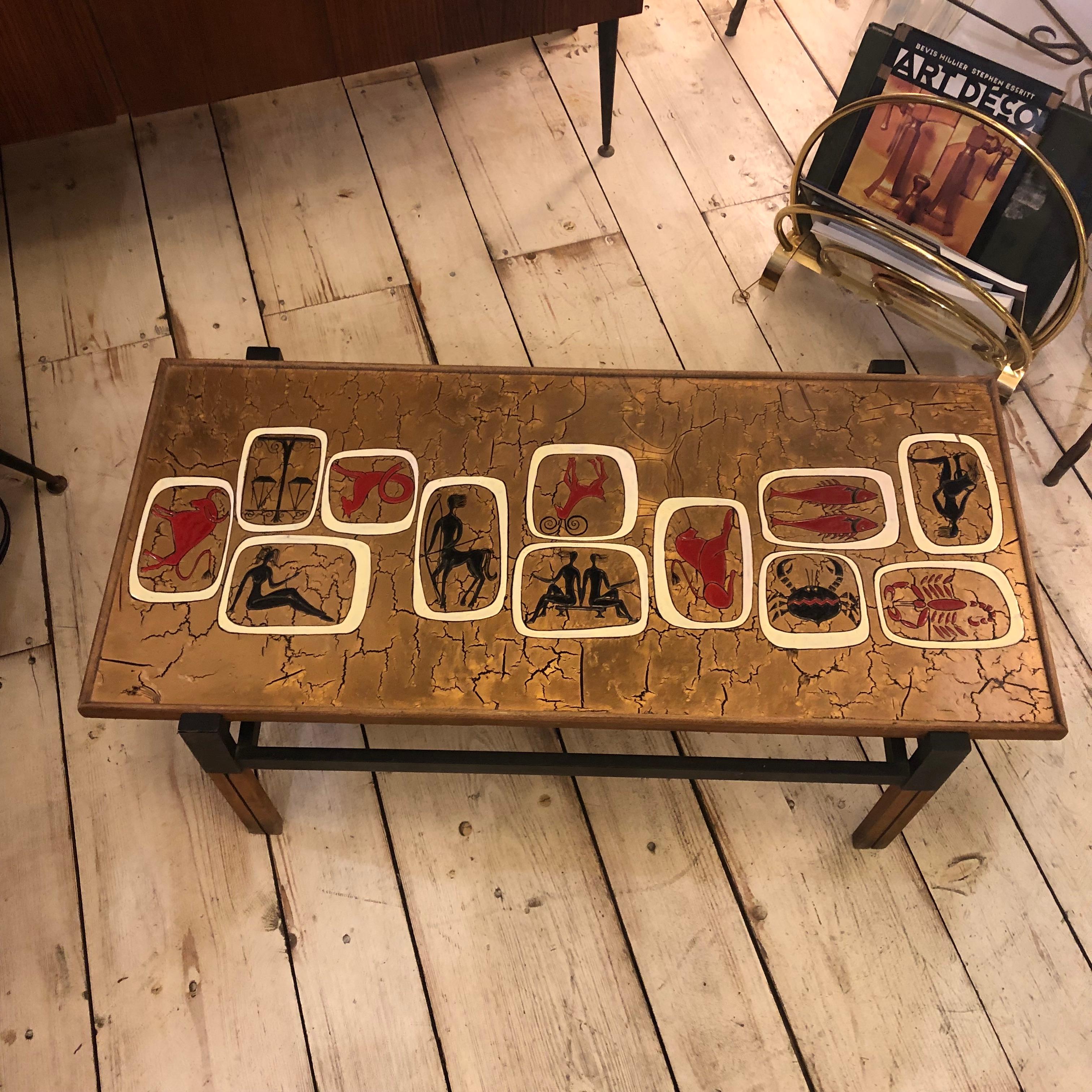 Particular gold enameled rectangular coffee table, with red and black zodiac signs. It's made in Italy in the Seventies.