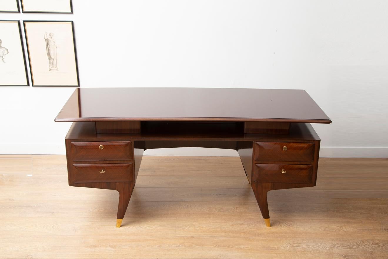 Mid-Century Modern Italian executive desk designed by Vittorio Dassi, 1950s.
Graciously curved Indian rosewood encasement with chevron pattern
Tapered legs with bronze sabots.
Featuring original burgundy inset glass top.
Four locking drawers