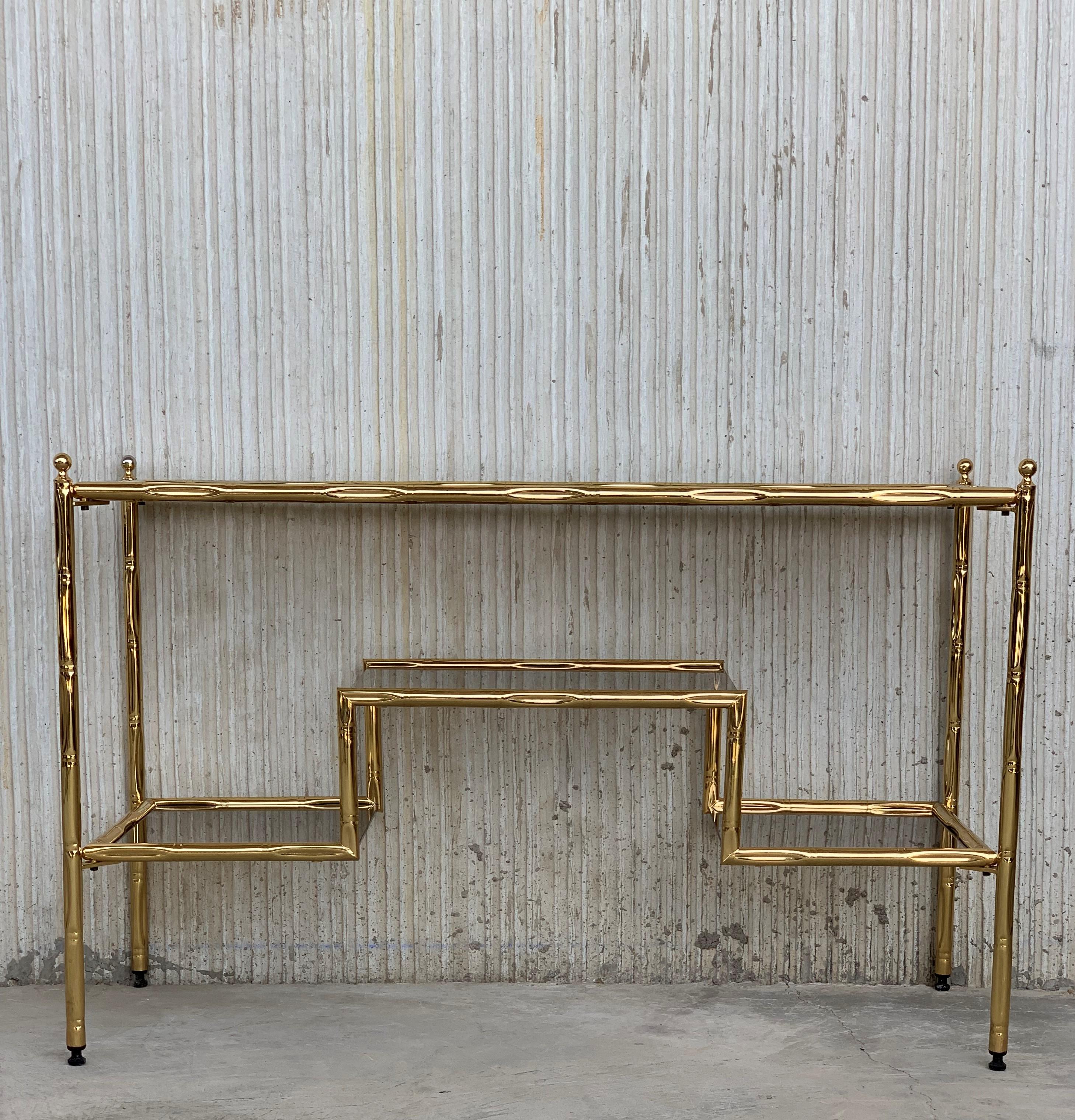 Mid-Century Modern Italian faux bamboo gilt metal console table or vanity with smoked glass.

Measures: Total height: 25.6in
Height to the glass top: 24.80in
Height to the middle glass shelve: 16.14in
Height to the low shelves: 9.45in.
