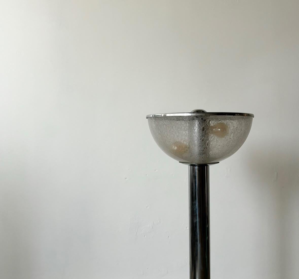 Ce remarquable lampadaire italien moderne du milieu du siècle dernier, datant des années 1970, incarne l'éthique du design épuré et innovant de l'époque. Fabriquée avec une combinaison raffinée d'acier et de verre, la lampe met en valeur un mélange