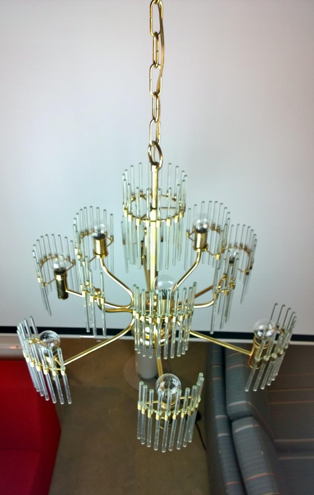 Offered is a Mid-Century Modern Italian Gaetano Sciolari brass frame and crystal rod chandelier. Sciolari lived and designed chandeliers in Italy. His pieces combined minimalism with high-glamour. His designs are comprised of shapes arranged in a