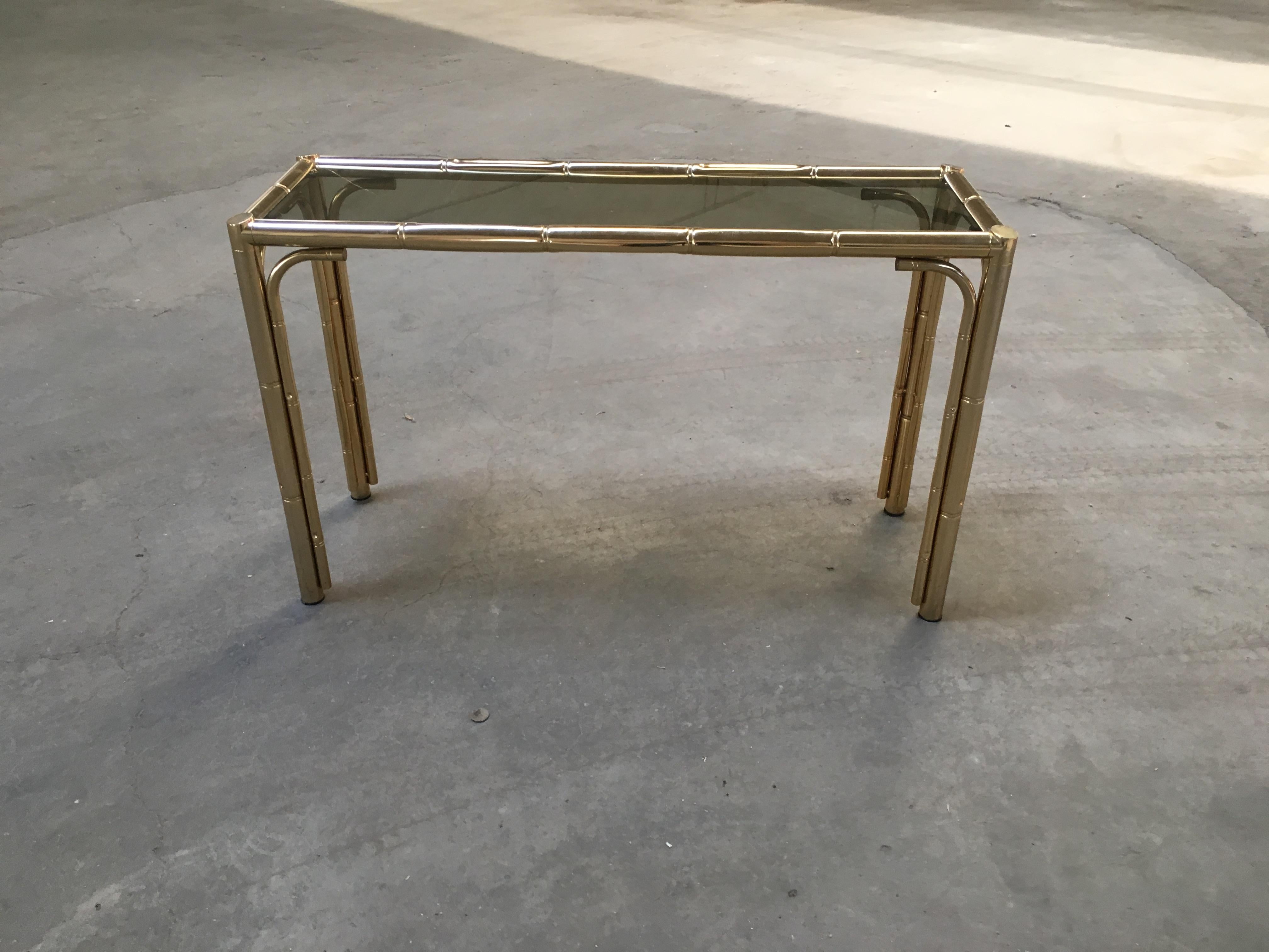 Mid-Century Modern Italian gilt finished faux bamboo console with smoked glass top.
This console could become a set together with its gilt finished faux bamboo framed mirror and one gilt finished faux bamboo étagère with glass shelves (see photo