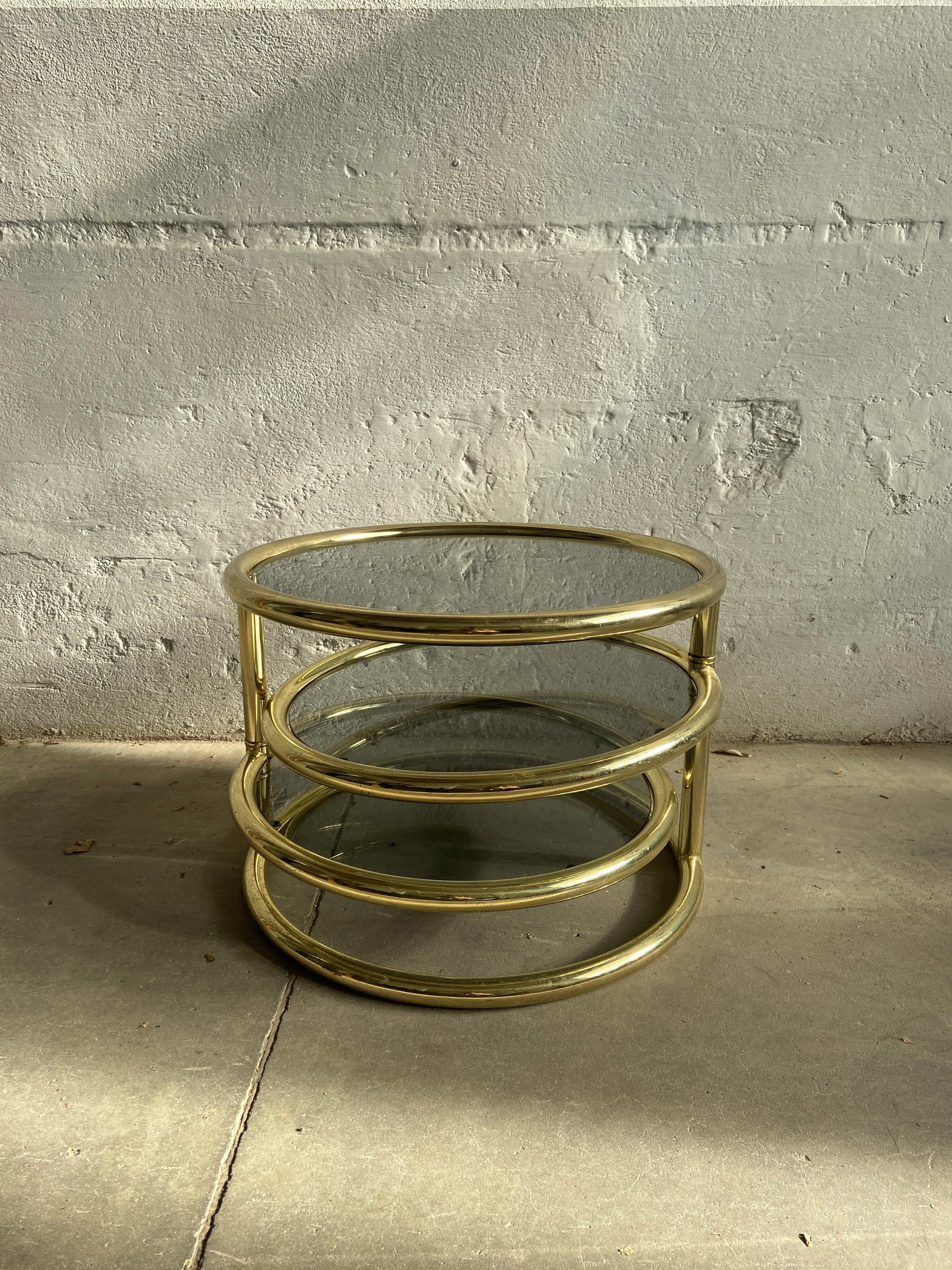 Mid-Century Modern Italian sofa or coffee table with three round smoked glass surfaced platforms mounted in Gilt Metal rings.
The adjustable two smaller rings allow you to place the table into various positions.
The table is in really good vintage