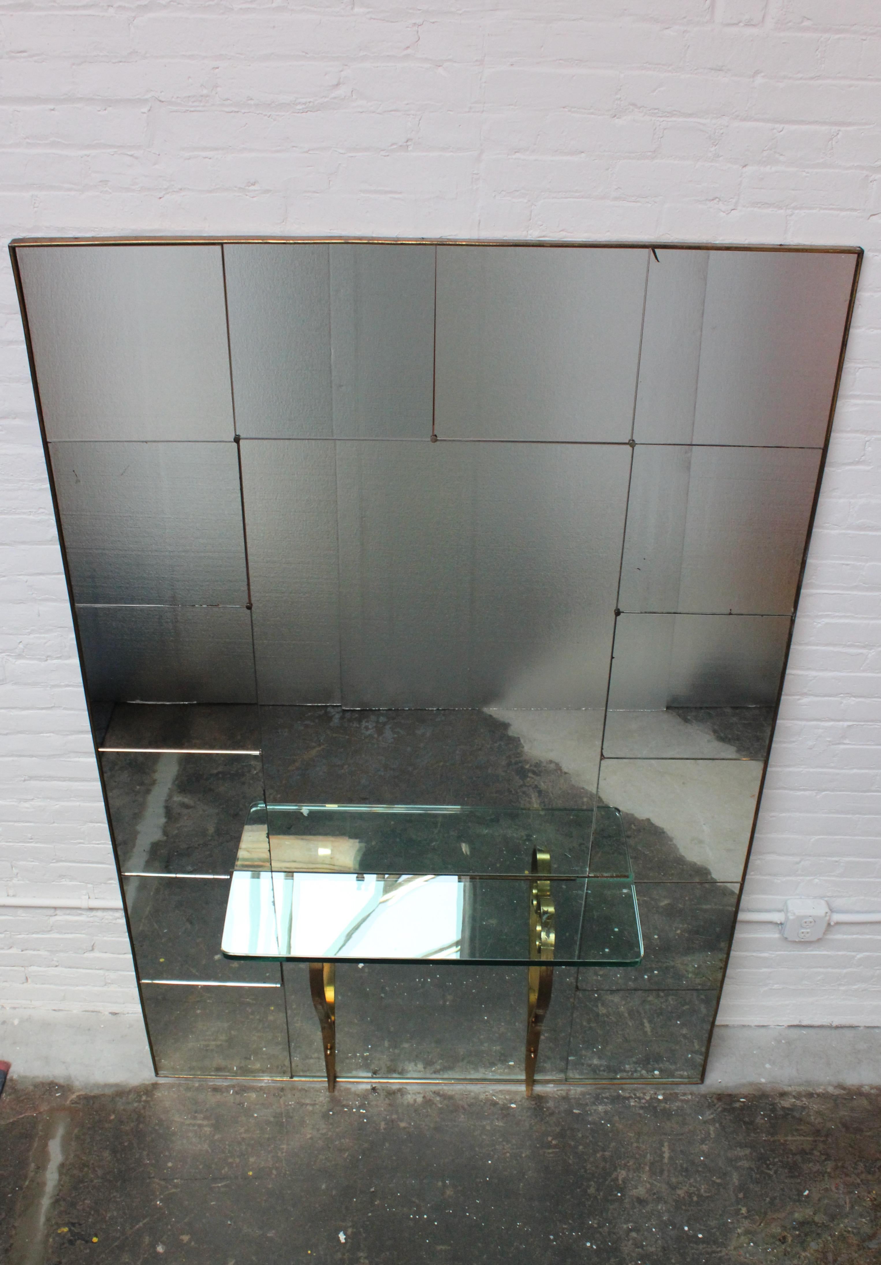 Sophisticated and elegant hallway mirror with tempered glass console table supported by two brass brackets (ca. late 1940s / early 1950s, Italy).
Brass lined wooden frame houses a total of sixteen mirrored inserts (fourteen squares lining the edges
