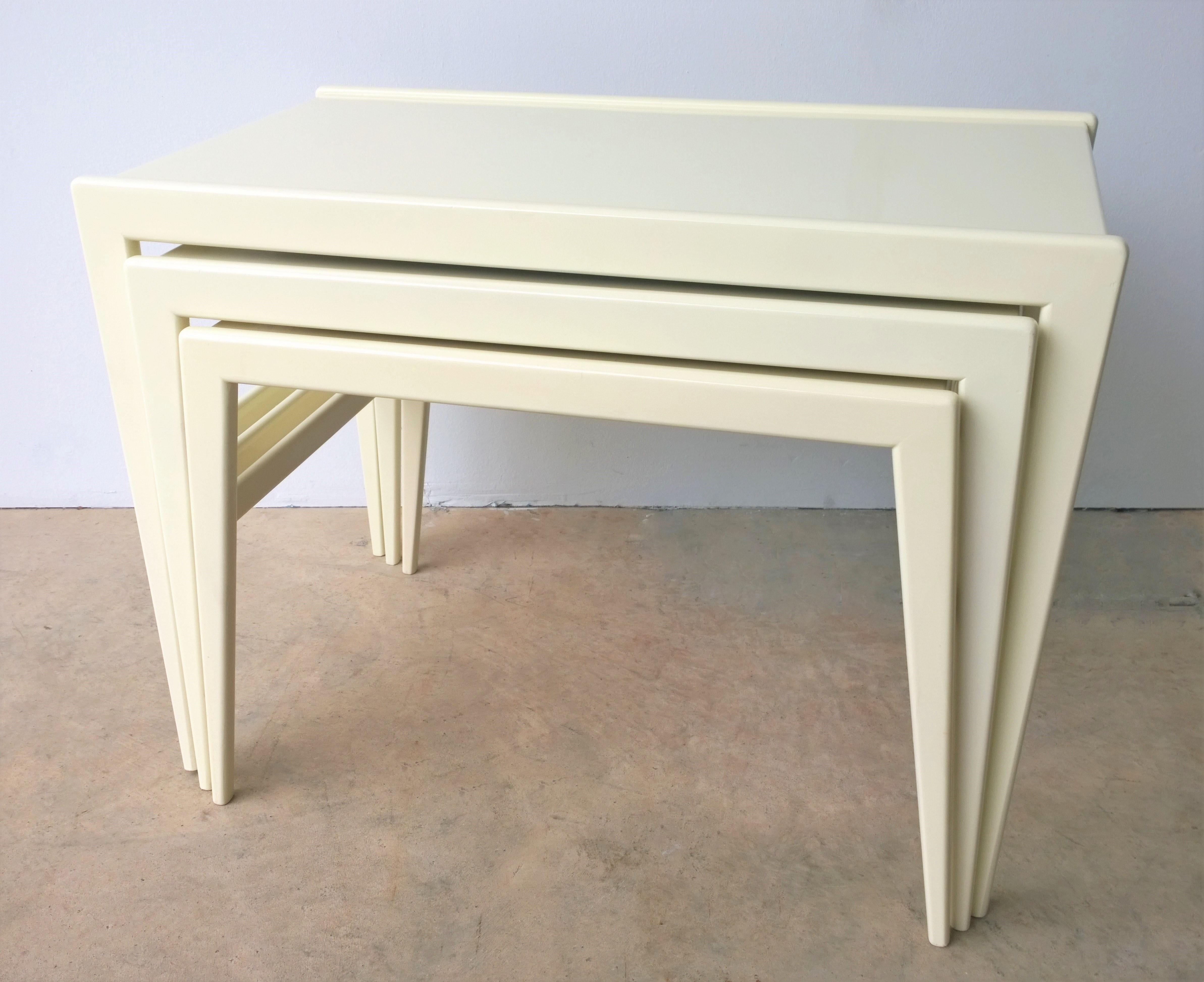 Offered is a set of three Mid-Century Modern Italian stacking tables newly lacquered in a luxurious creamy white wood designed by Ico Parisi for Singer & Sons. The set of three stacking tables would look fabulous in almost any setting with any style