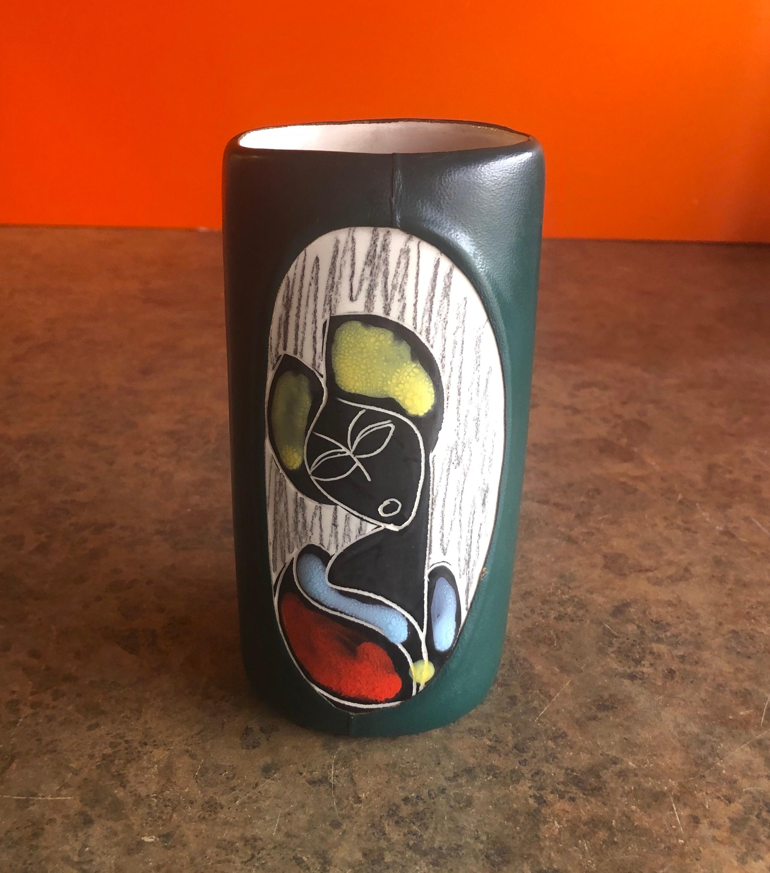 Mid-Century Modern Italian leather wrapped ceramic vase in the style of Marcello Fantoni, circa 1970s. The white ceramic vase is wrapped in forest green leather and has the image of a woman on the front side. It is 6