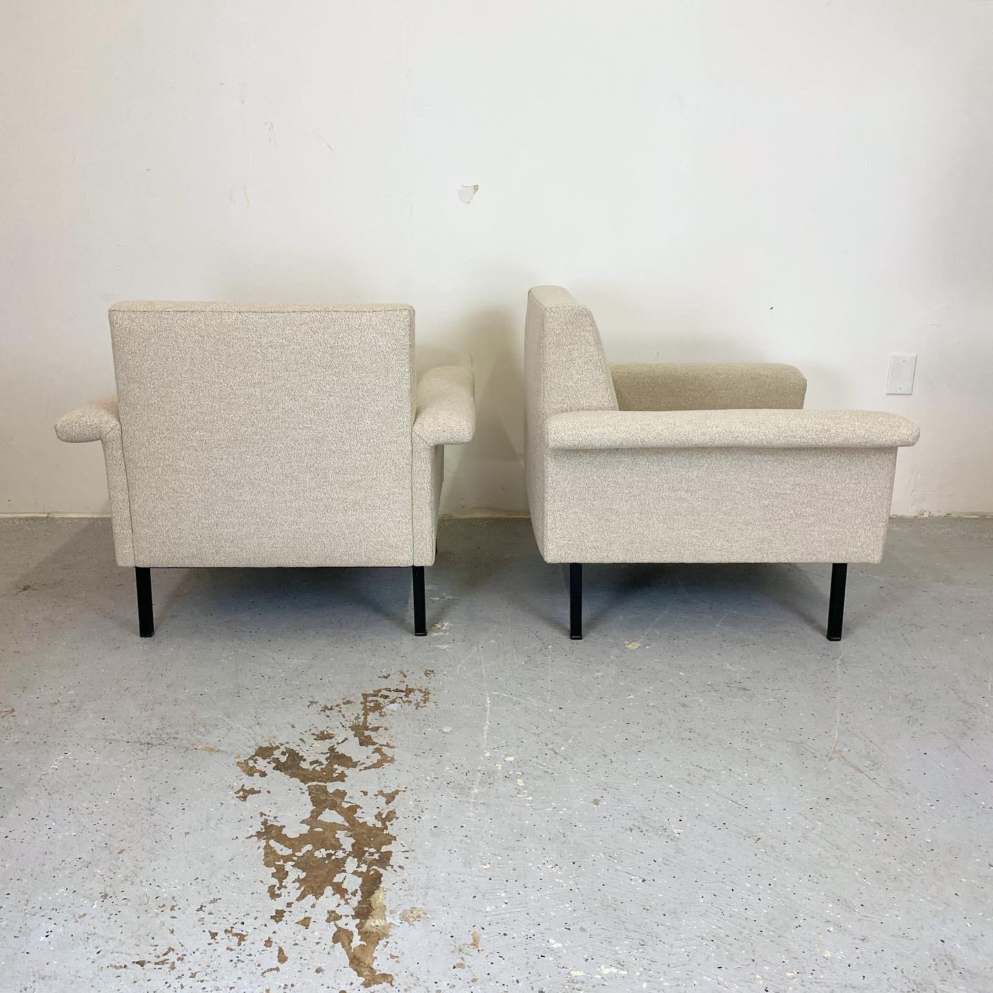 This mid century pair of club chairs have been expertly reupholstered in a soft oatmeal boucle. They have a great architectural look with a wide stance. The welded steel frame has been left in its original paint which shows age and patina. A great
