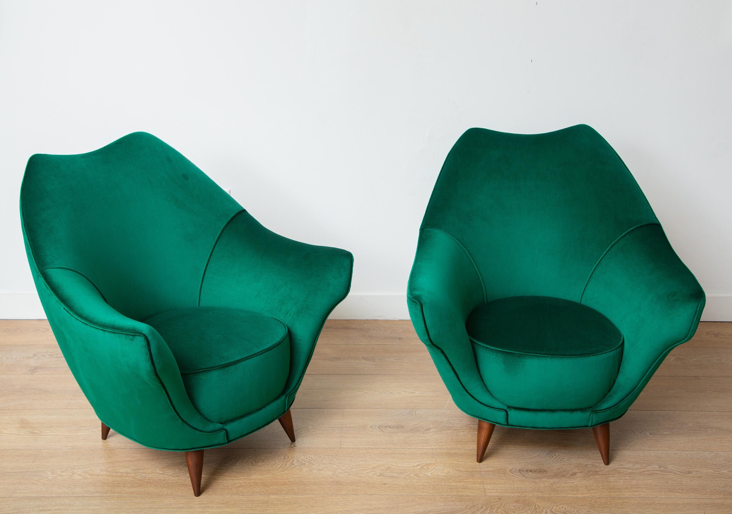 Pair of mid-century modern Italian lounge chairs in Emerald green velvet
Newly upholstered with an emerald green velvet 
Walnut finish conical wooden legs.
 Italy, circa 1950. 
Restored to perfection by our local artisans.
Located in our store in