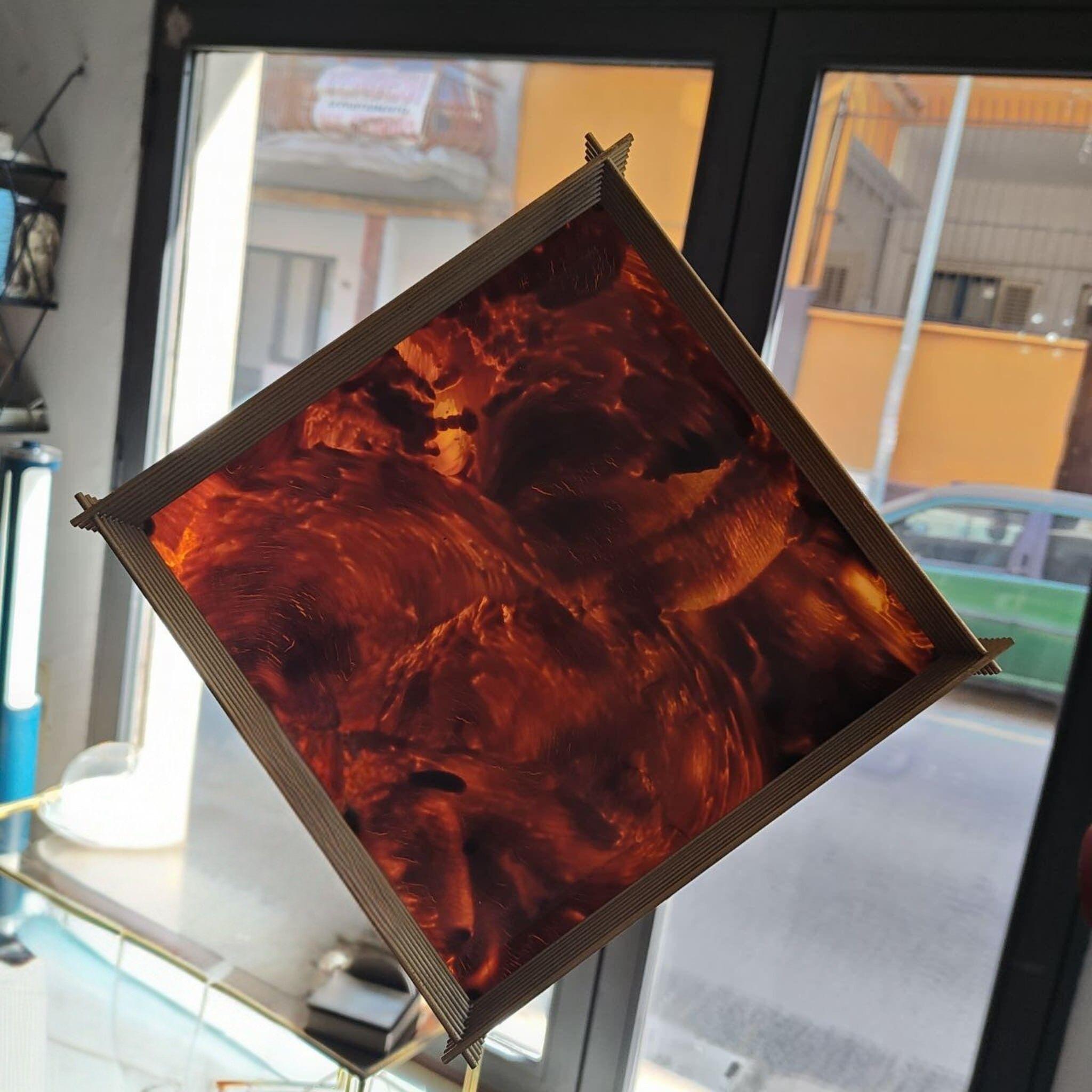 Questo vassoio portaoggetti, squisito esempio di design italiano del Mid-Century degli anni '70, è realizzato in lucite (resina acrilica) dalle tonalità calde con un ricco effetto tartaruga che va dall'ambra al marrone intenso. La forma quadrata (25