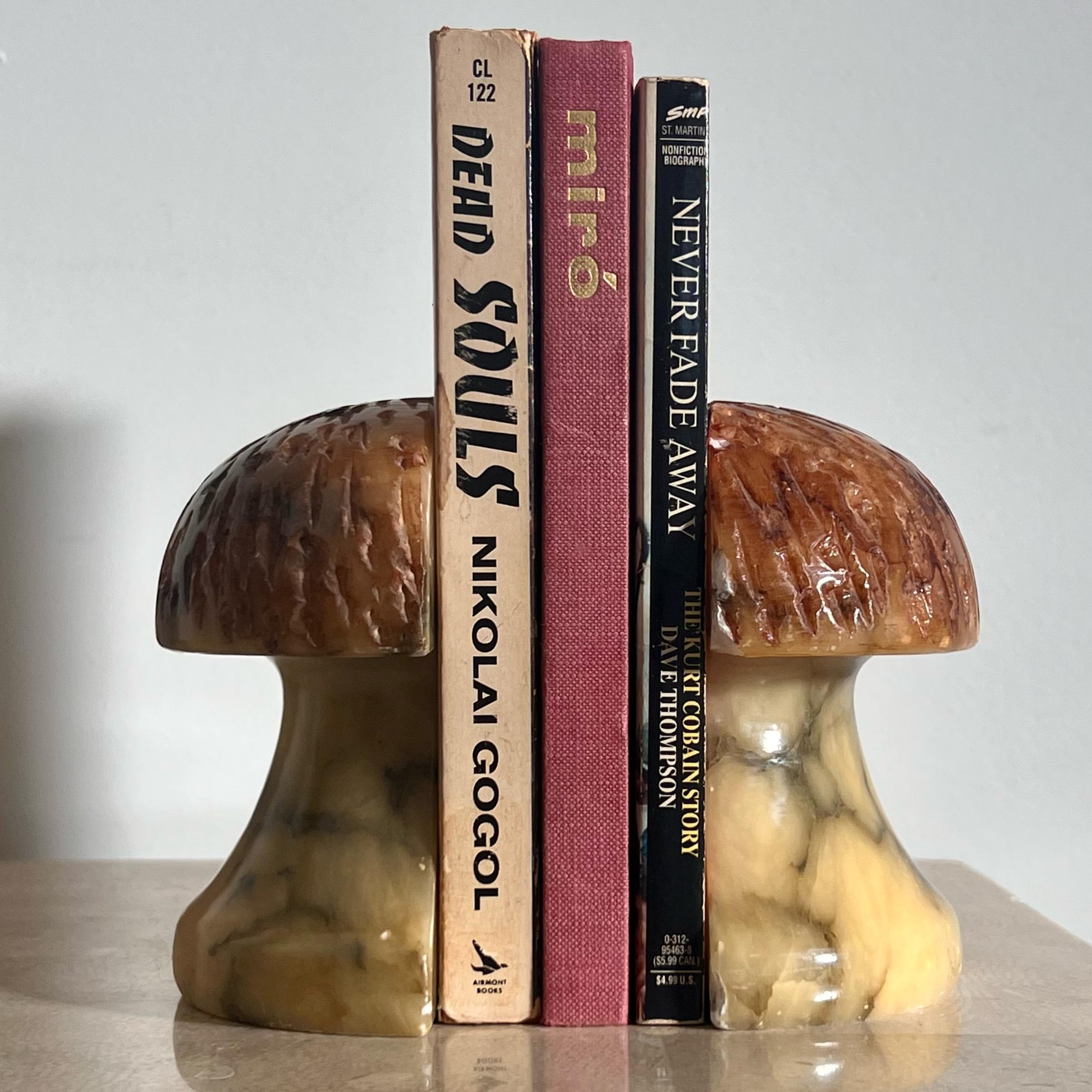 A pair of mid century modern vintage Italian alabaster marble bookends, hand-carved in the shape of mushrooms, circa 1960s. Bases are smooth and in tones of eggshell with charcoal veining, while tops are textured and of a chestnut colored hue. There