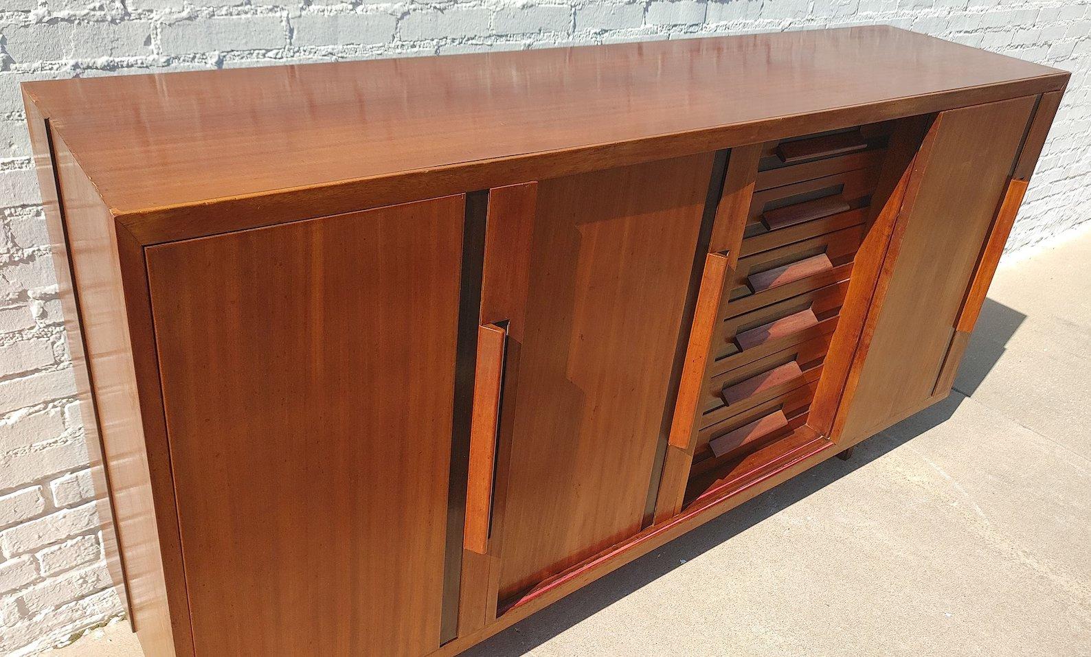Mid Century Modern Italian Modern Teak Cabinet

Average vintage condition and structurally sound. Has some expected finish wear and scratching. Several of the sliding doors have splits in the lower part of the door. Has some veneer chips on edges in