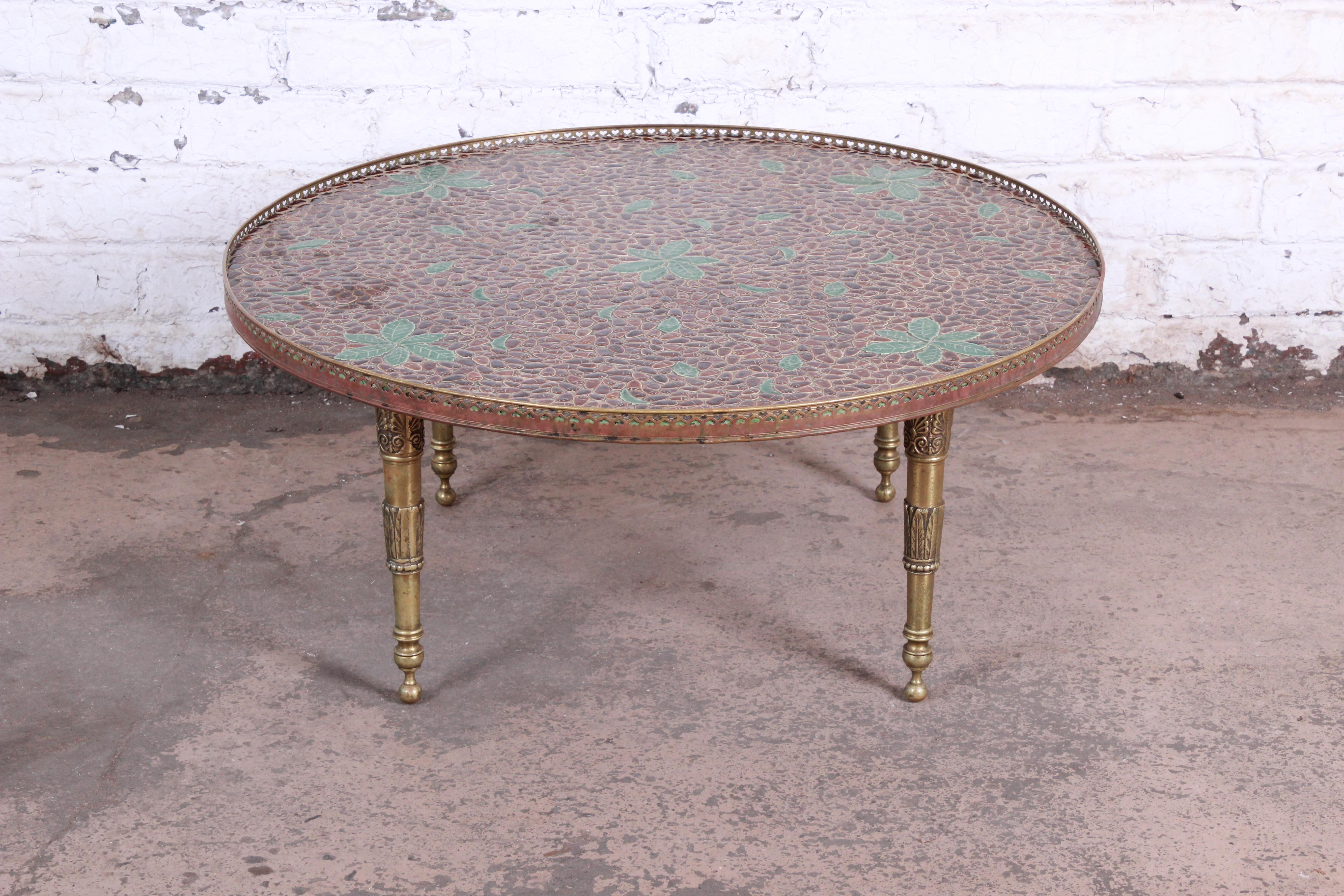 A gorgeous Mid-Century Modern Italian coffee or cocktail table. The table features a unique mosaic tile top in acorn and leaf motif, with sculpted brass legs and a brass gallery. Truly a one-of-a-kind statement piece. Made in Italy, circa 1950s. The