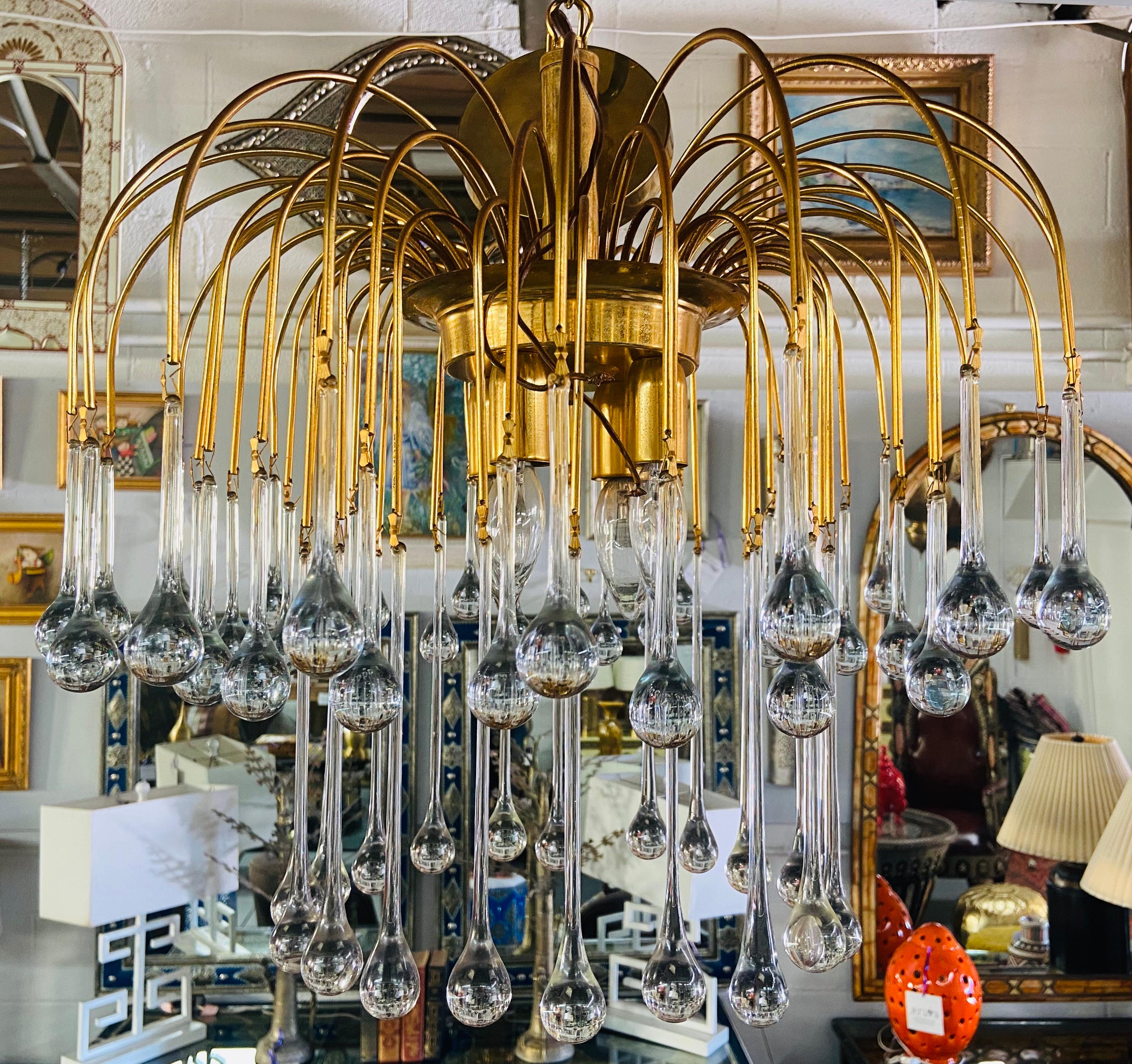 And elegant Mid-Century Modern Italian Murano crystal teardrop waterfall chandelier that will add sophistication and style to any living space. The chandelier takes 4 chandelier bulbs. Made in Italy in the 1950s, this chandelier is made of brass and