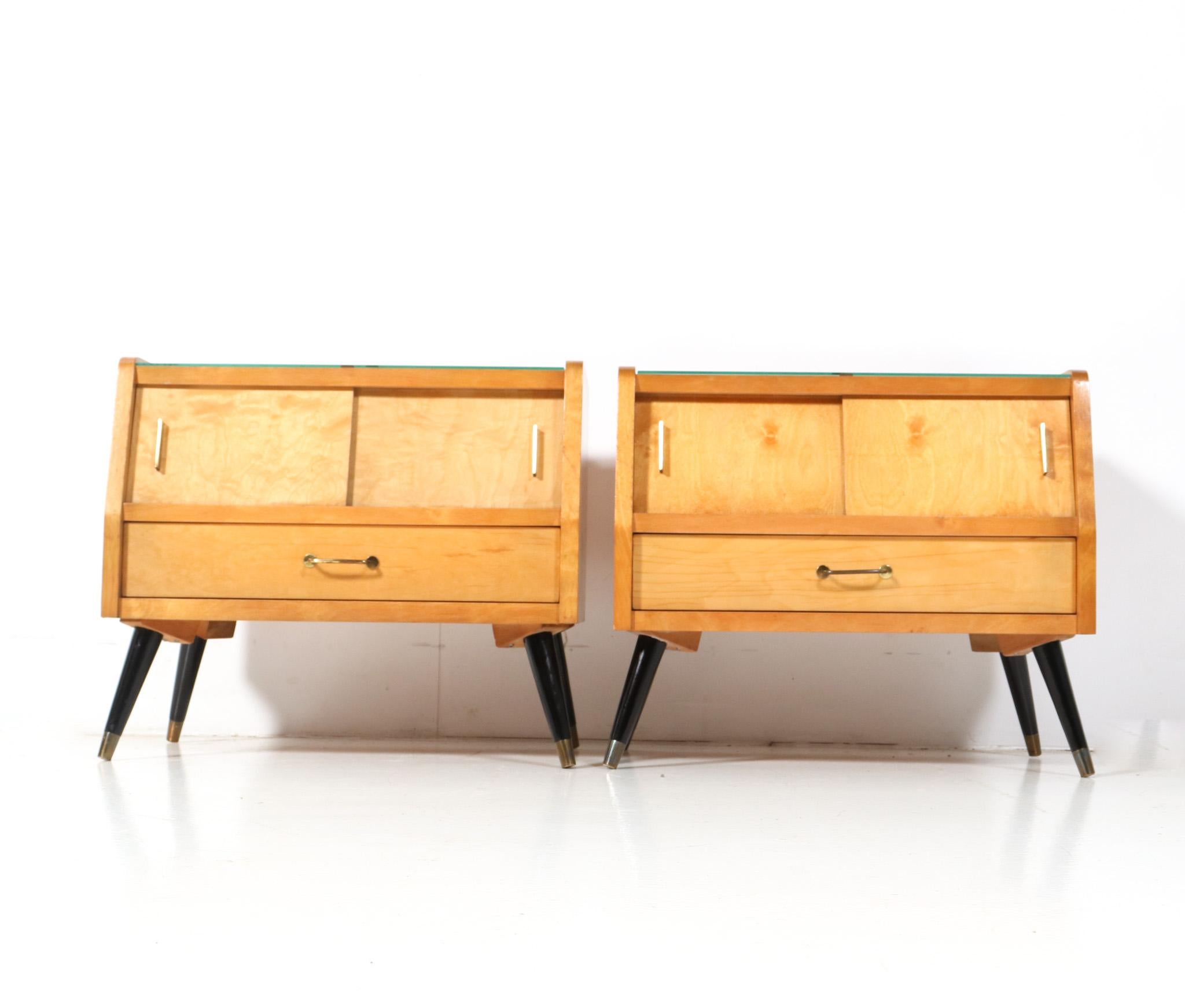 Stunning and rare pair of Mid-Century Modern nightstands or bedside tables.
Striking Italian design from the 1960s.
Solid birch and original veneered birch base on original black lacquered and brass feet.
The sliding doors and drawers have the