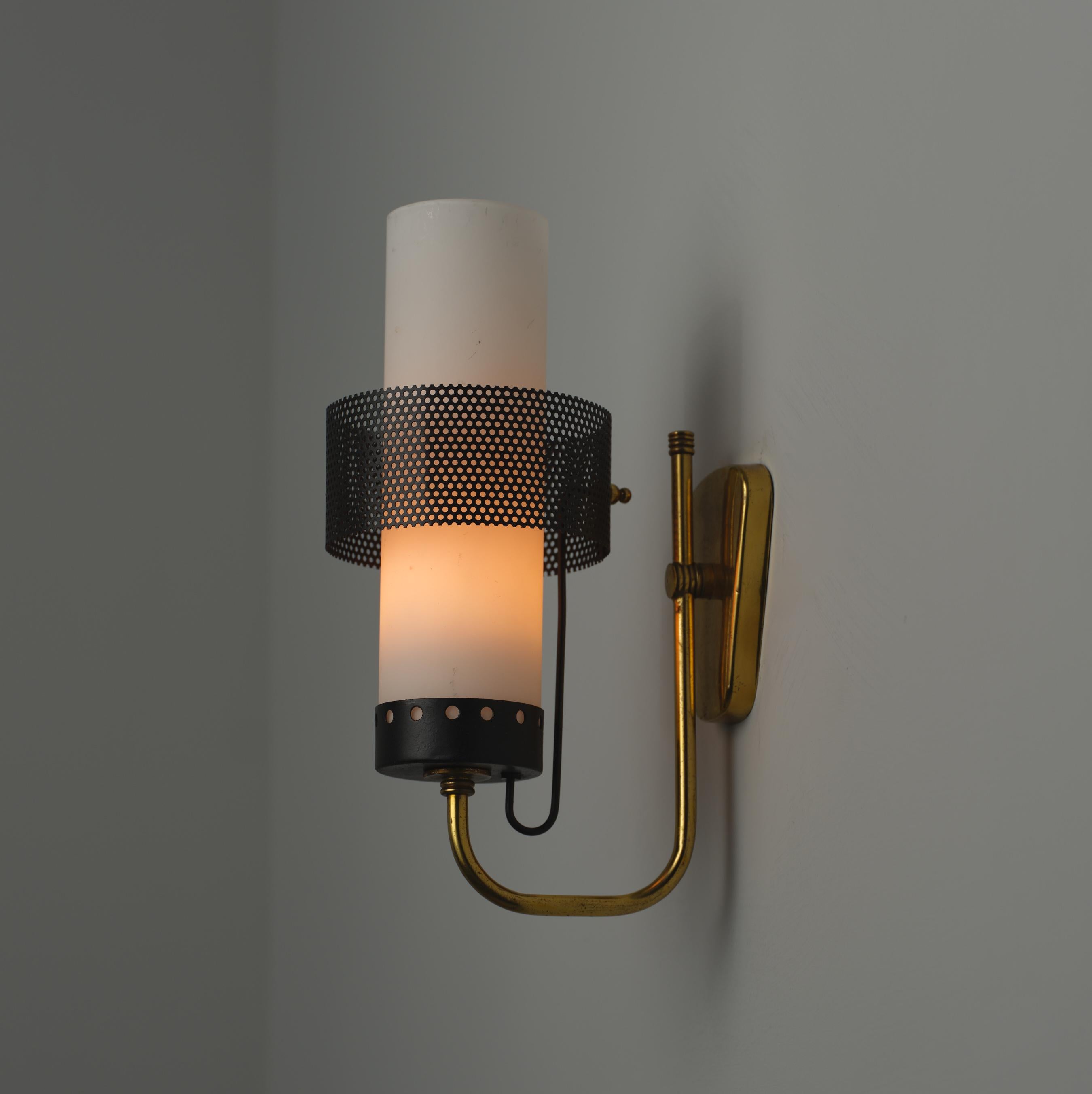 This mid-century modern sconce, designed and produced in Italy during the 1950s, embodies an elegant and contemporary aesthetic. Constructed with brass and featuring black lacquered perforated sheet metal and black lacquered metal elements, this