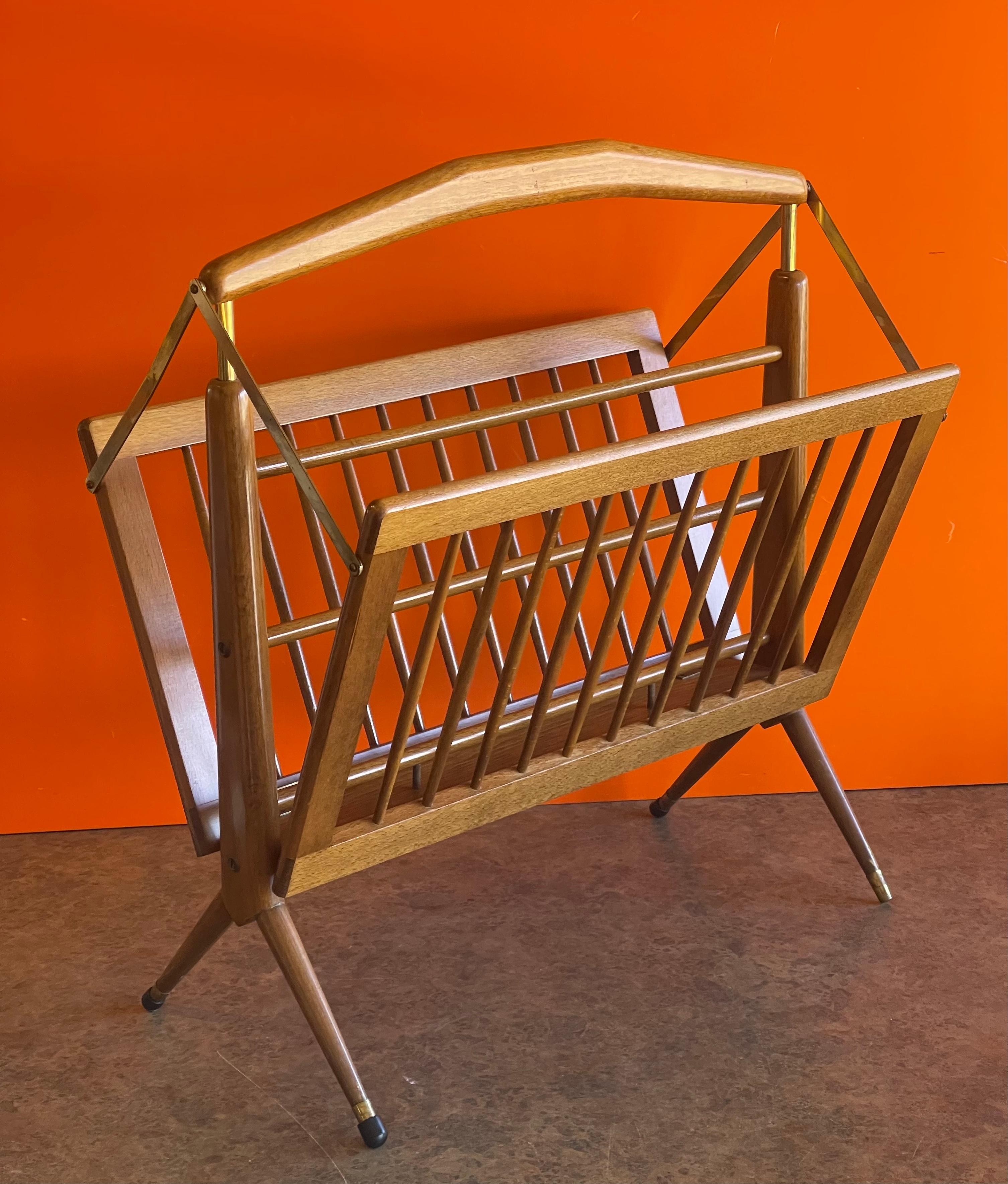 Mid-Century Modern Italian solid walnut and brass foldable magazine rack by Cesare Lacca, circa 1950s. This ingenious design allows the magazine rack to fold up with the lift of the handle; very east to move and manage. The piece is in very good