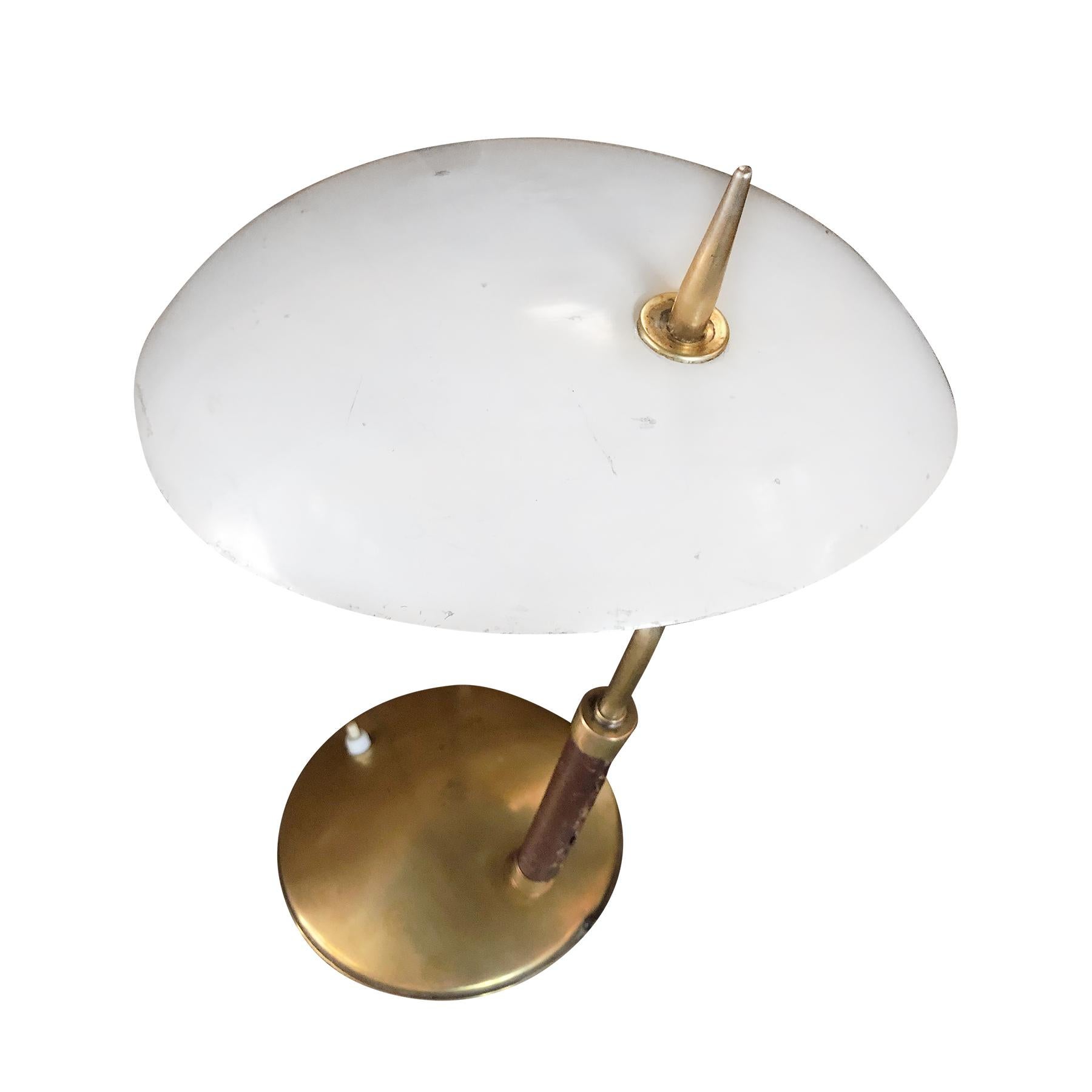 A vintage Mid-Century Modern Italian small desk lamp or table lamp made of lacquered metal and brass with a white adjustable oval lamp shade, featuring a one light socket. Produced by Stilnovo in good condition. The lamp neck is covered in dark