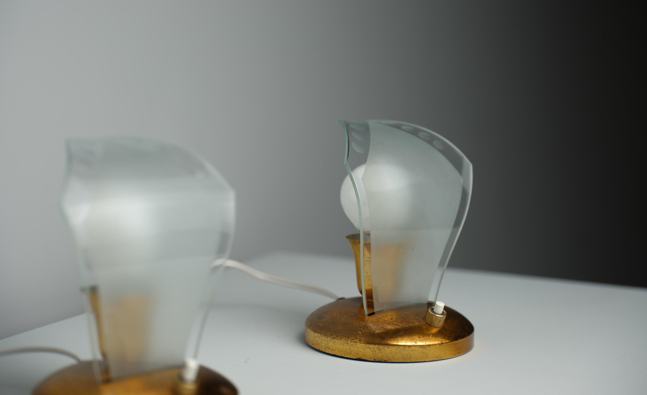Questo set comprende due lampade da tavolo, prodotte in Italia negli anni '60, che riflettono l'estetica del design e la maestria dell'epoca. Ogni lampada è dotata di una robusta base in ottone che presenta una patina naturale che ne suggerisce