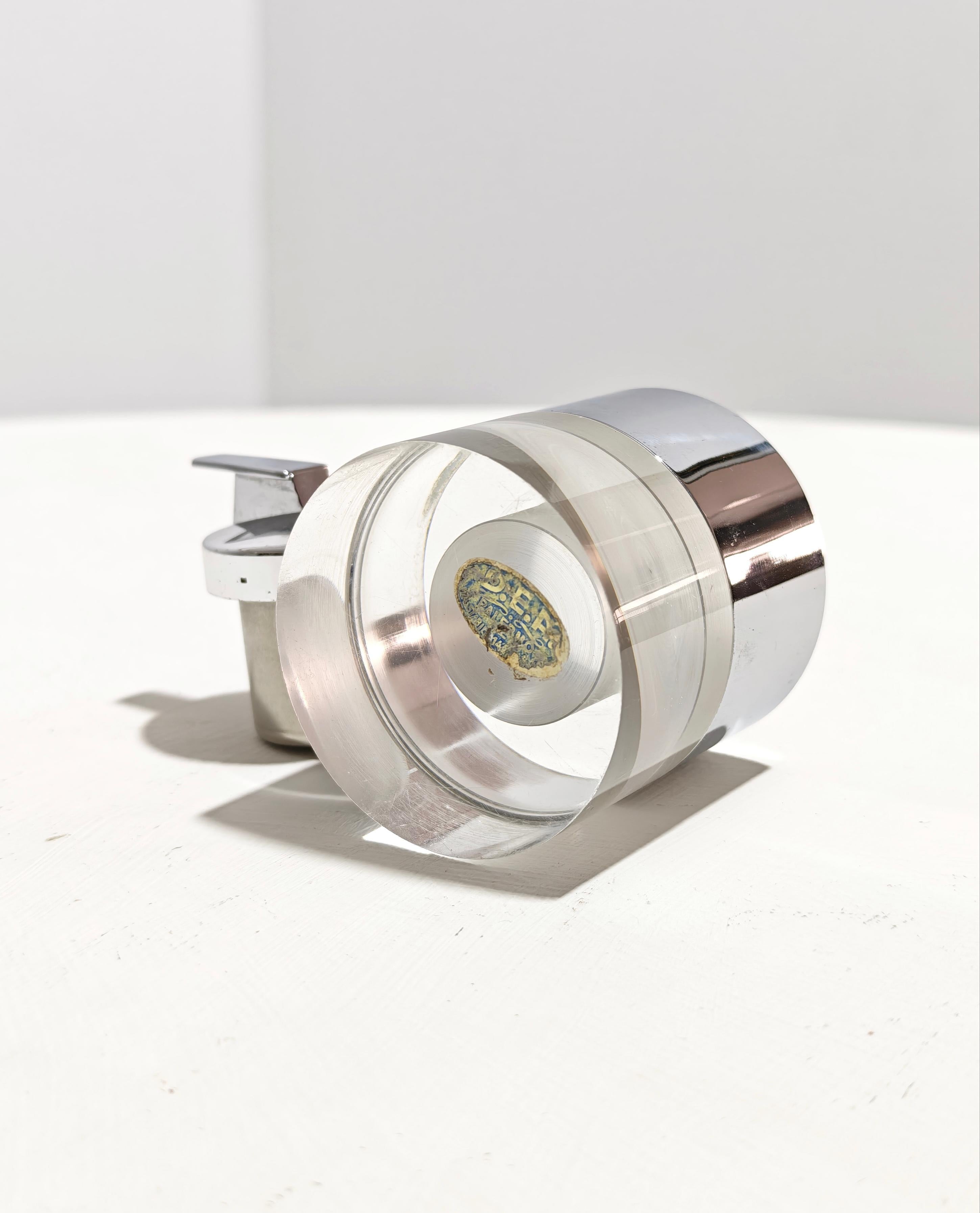 Plexiglass design table lighter with chrome band accessory a really beautiful accessory. Cylinder body. Made in Italy in the 70s. Perfectly functional. Please watch the video and photos carefully, thank you.

Weight: 0.500 Kg

NOTE: We offer our