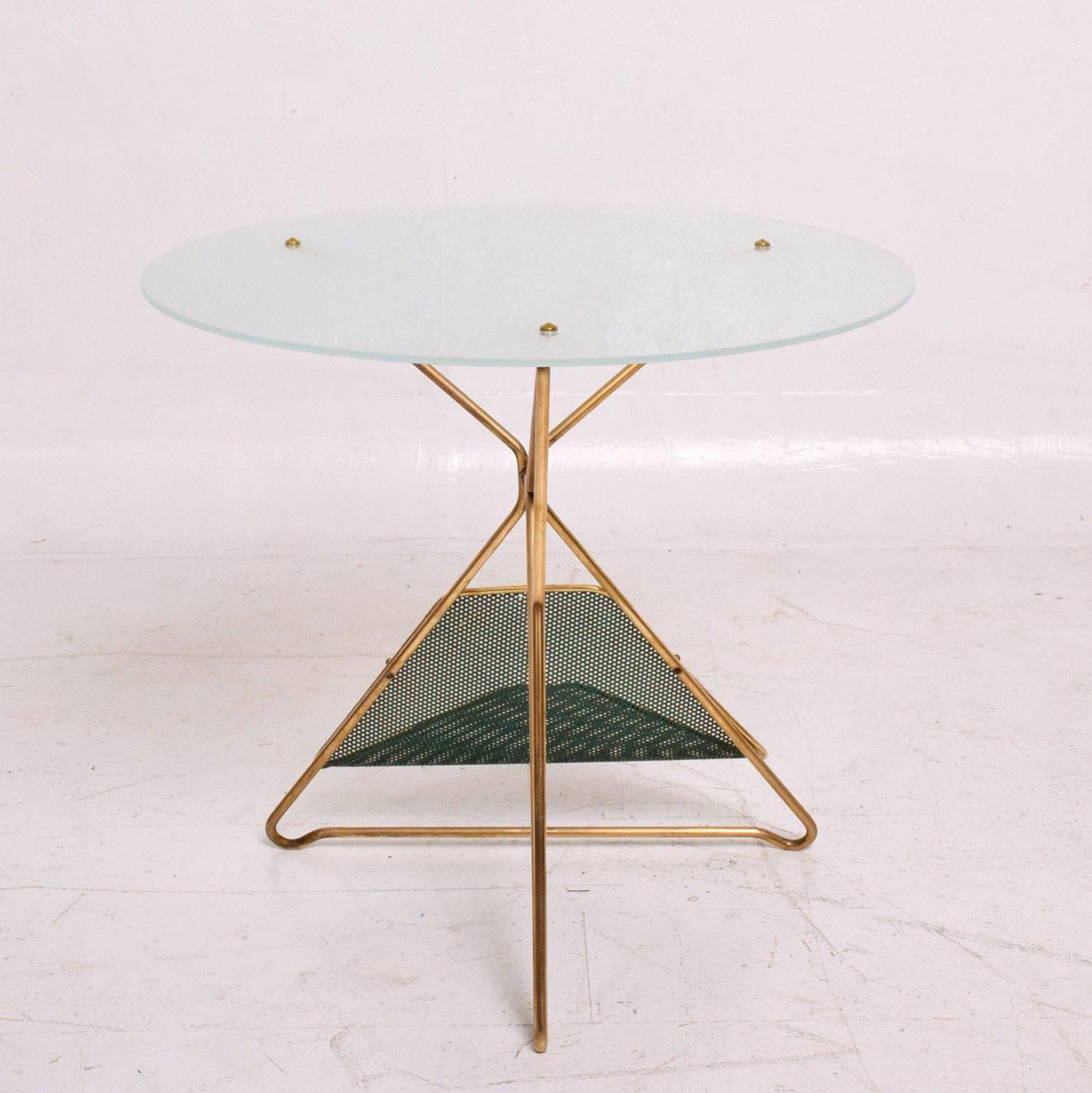 For your consideration a vintage Mid-Century Modern round table constructed with sculptural brass base and frosted round glass top.
The base has a perforated metal (painted in green with brass trim) magazine holder.

Beautiful unique design.
