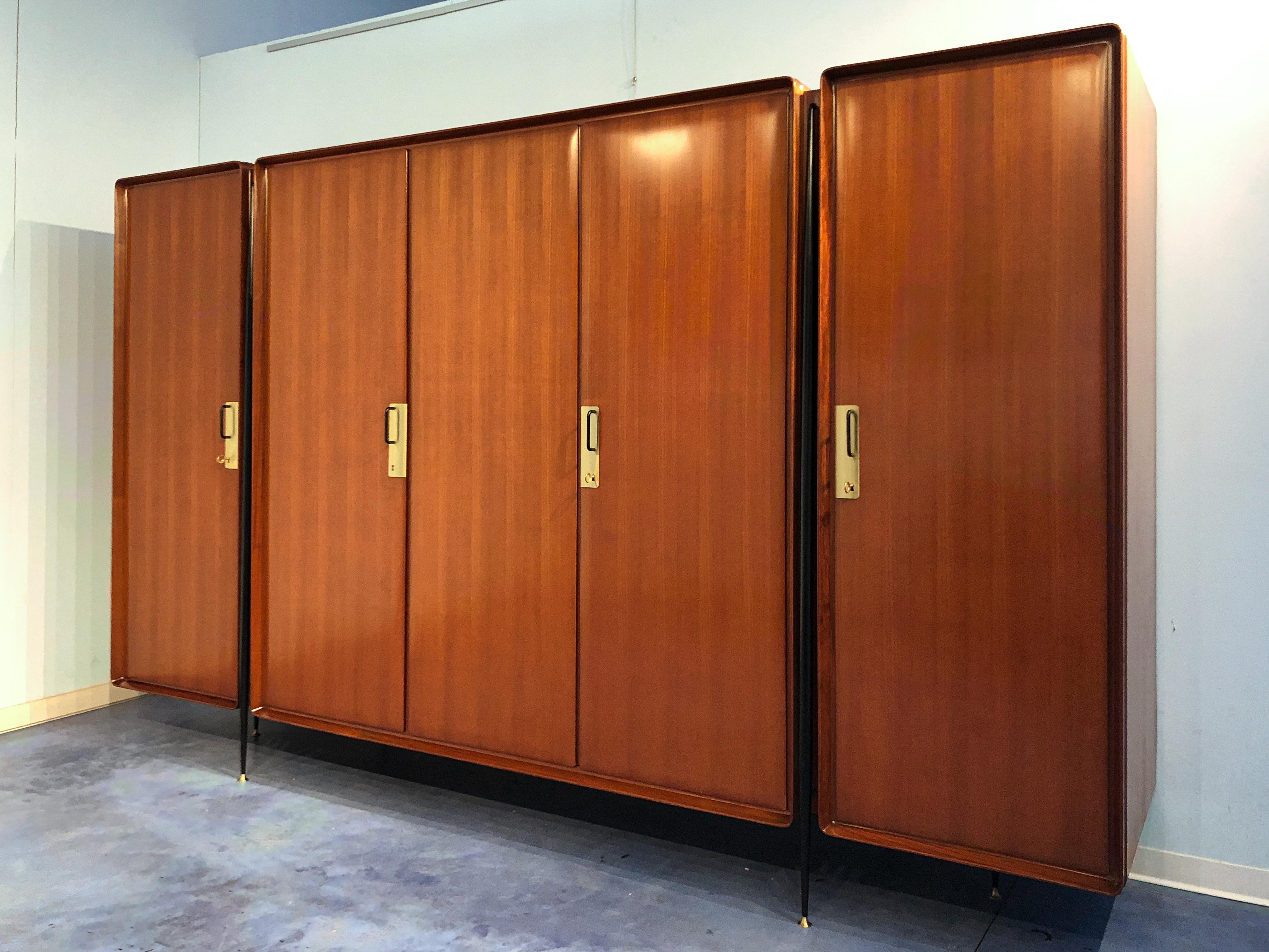 Stylish Italian wardrobe designed by Silvio Cavatorta in the 1950s.
The cabinet is made of semi-gloss lacquered teak veneer with five doors finished with brass details, supported on tapered steel legs with brass feet.
Internally it offers a lot of