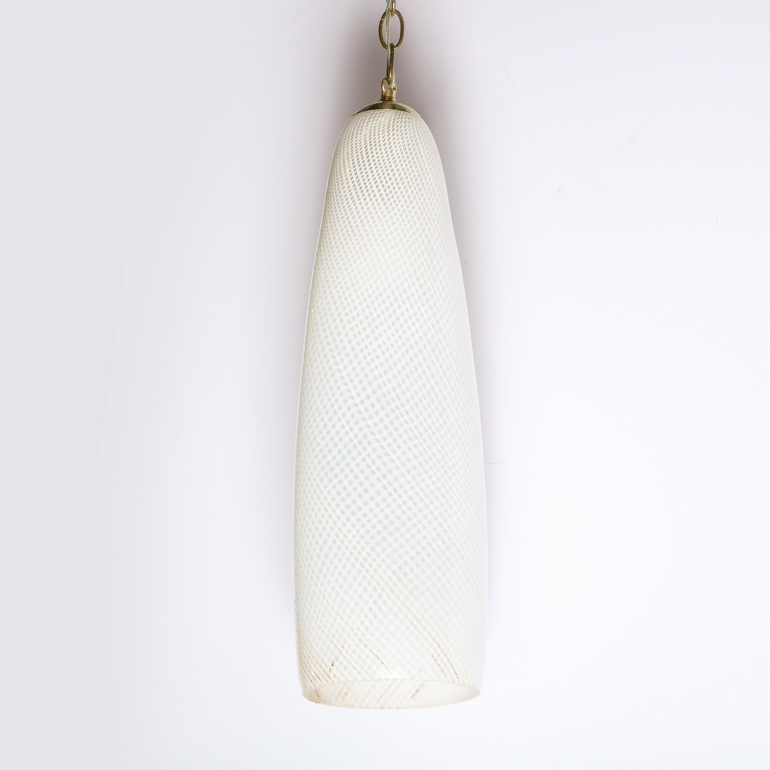 This elegant Mid Century Modern pendant was realized in Murano, Italy- the island off the coast of Venice renowned for centuries for its superlative glass production- circa 1960. It features a cylindrical form that tapers subtle at each end that