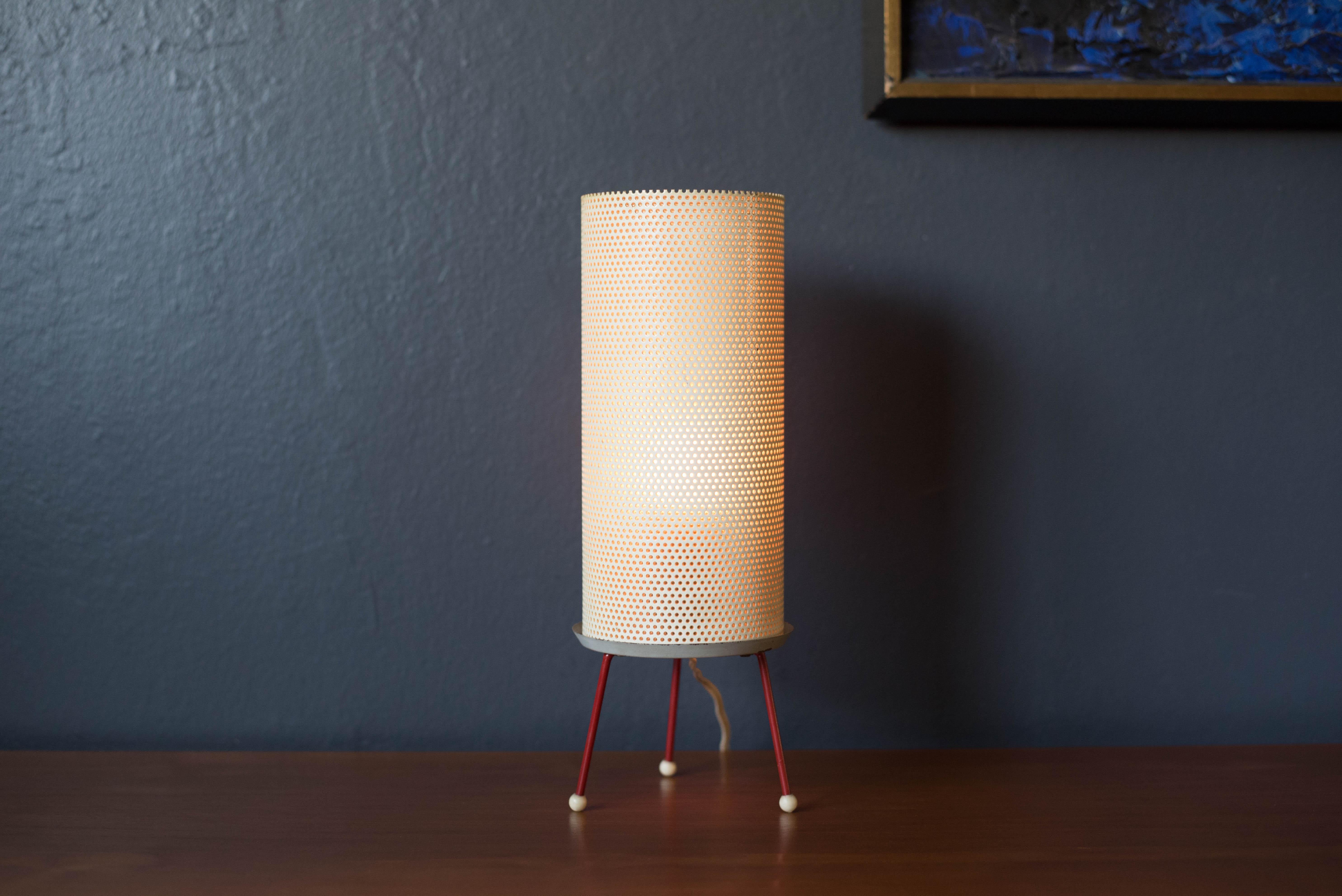 Vintage atomic tripod table lamp, circa 1950s. This unique piece features a cylinder perforated metal shade supported by a red tripod base. Perfect to use at a desk or as a reading light.