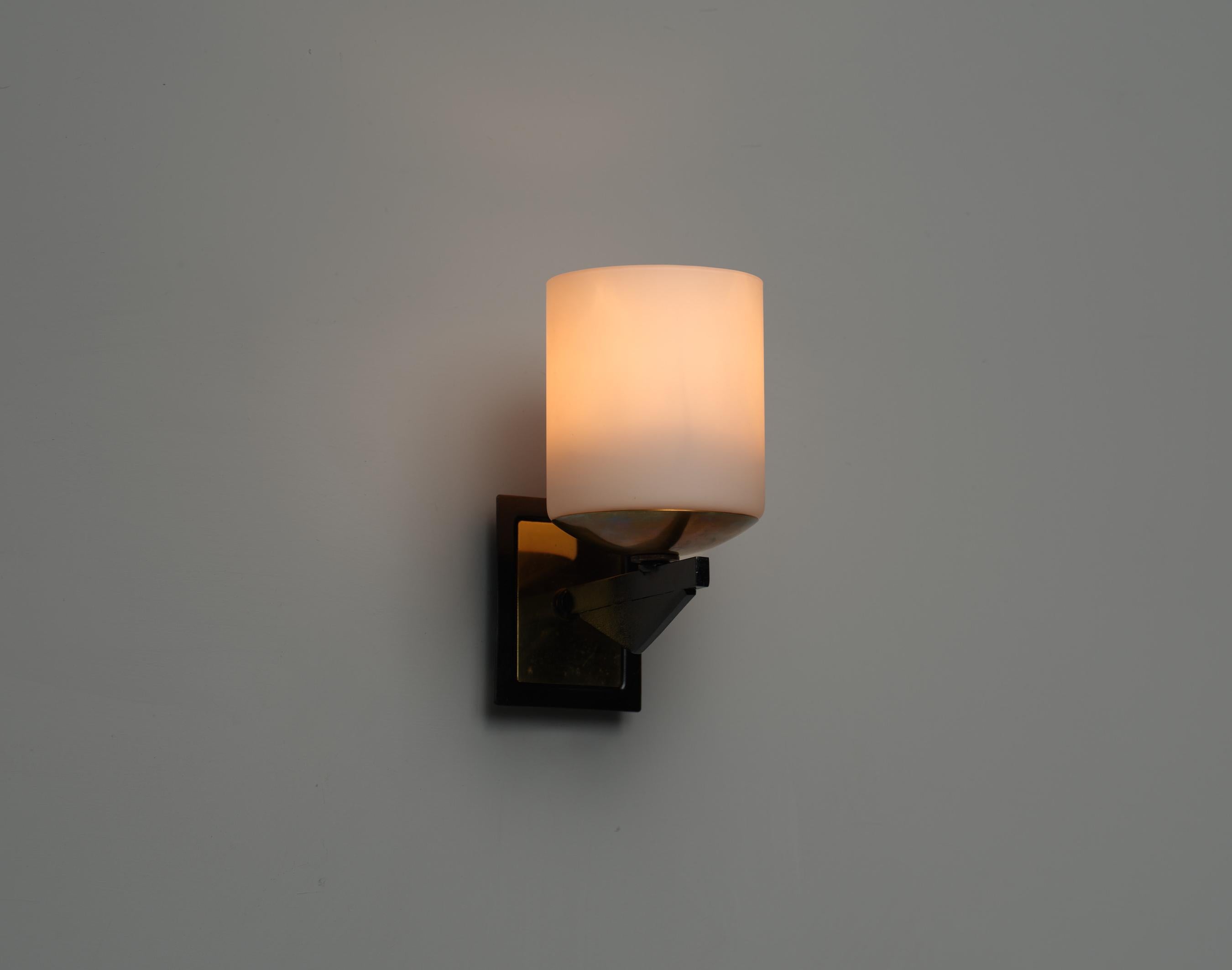 Este conjunto de apliques de pared italianos de los años 50 ejemplifica la elegancia moderna de mediados de siglo. Cada candelabro presenta un diseño robusto con materiales que incluyen metal negro lacado y latón, complementados con pantallas de