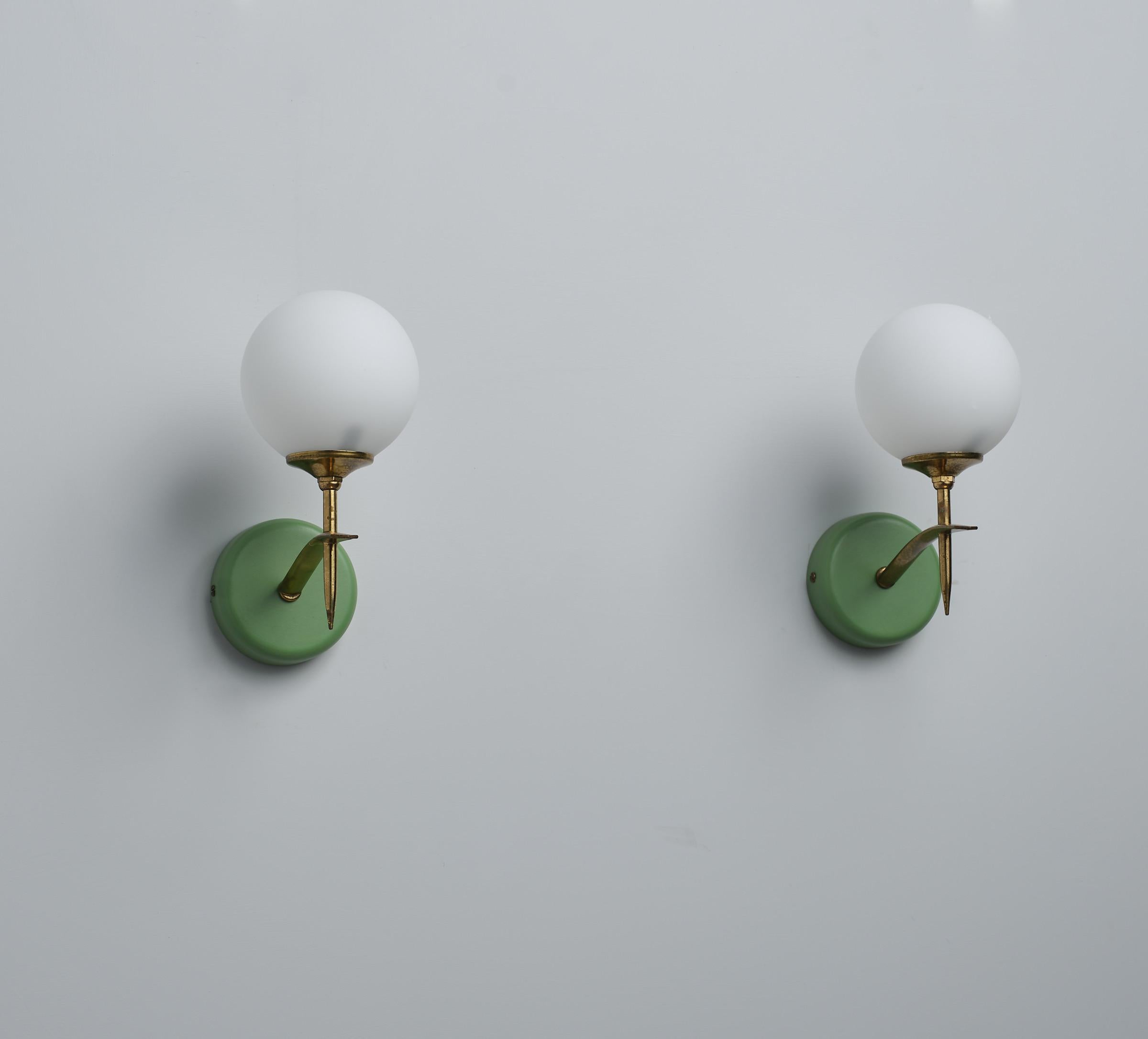 This sophisticated pair of Italian wall sconces, designed in the 1950s, captures the essence of modernist elegance. Constructed from brass with an original patina that adds character and depth, the sconces are mounted on brass wall fixtures,