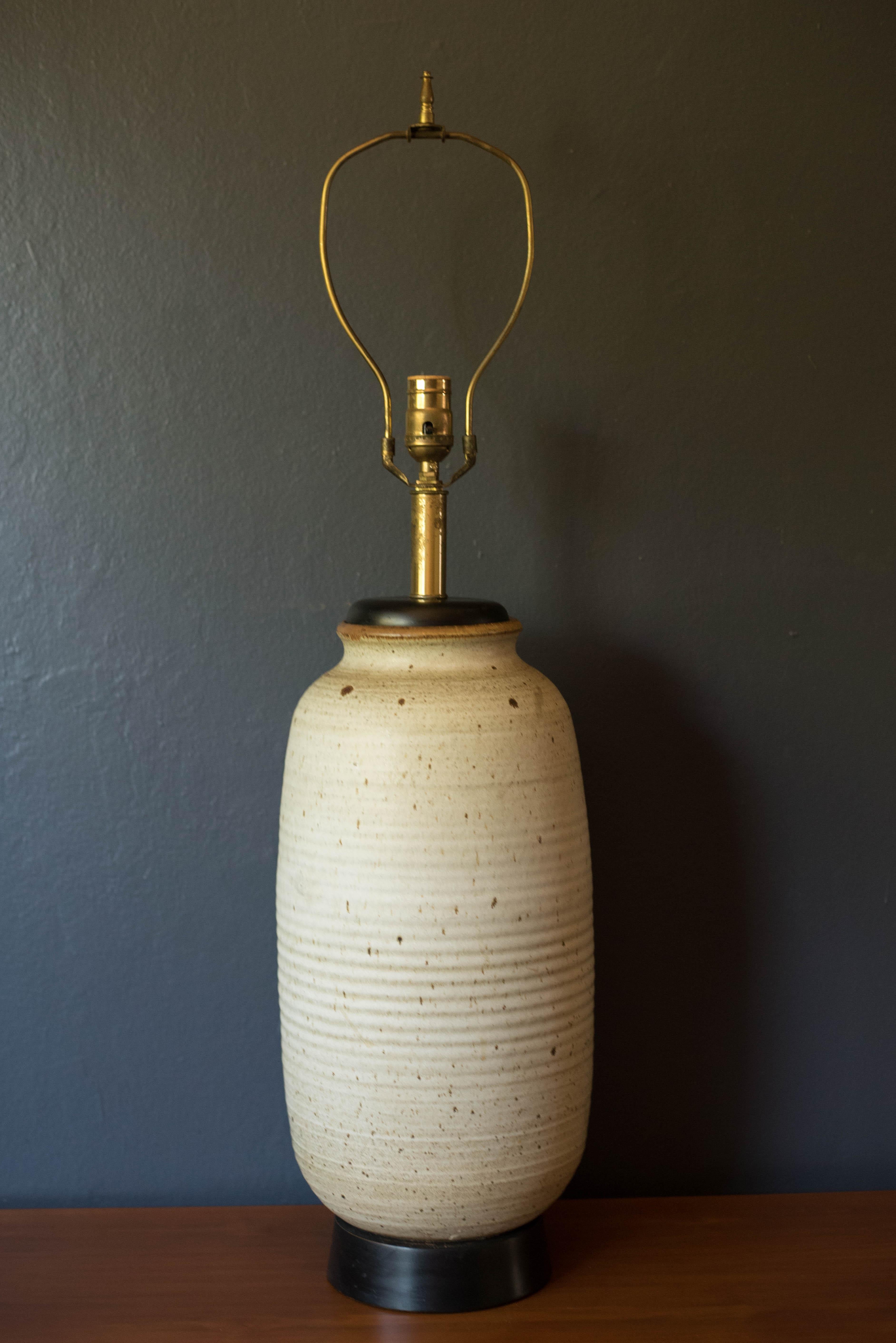 Lampe de table vintage des années 1960 en céramique texturée avec un design de tons de terre naturels. Cette pièce se caractérise par une base à gros renflements, émaillée d'une finition ivoire mate mouchetée et d'accents en bois laqué noir. Emet