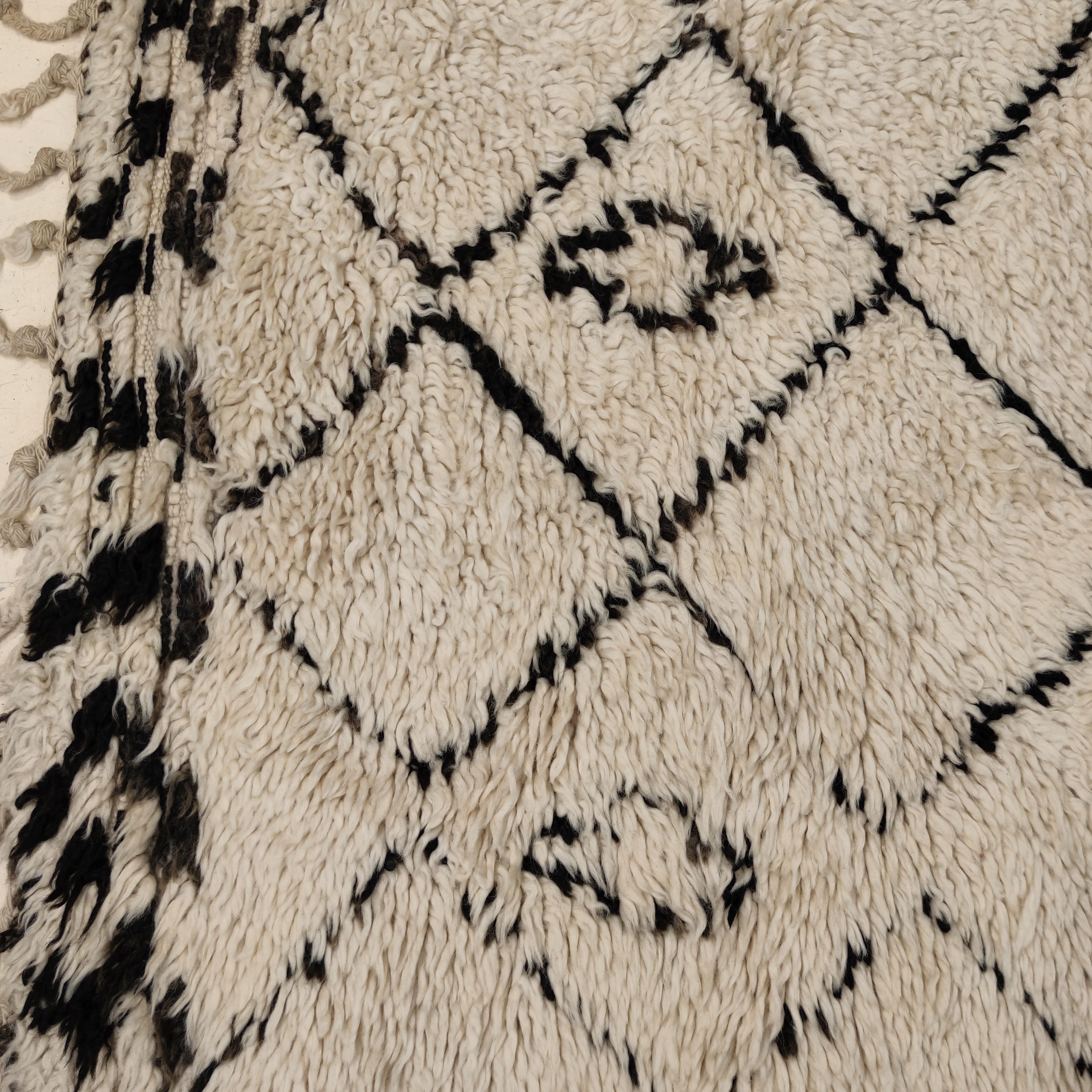 The rugs of the Beni Ouarain tribal confederacy differ from other Berber weavings in that they are woven almost exclusively on an ivory background and decorated with abstract geometric motifs in undyed natural brown/black wool. The pattern is