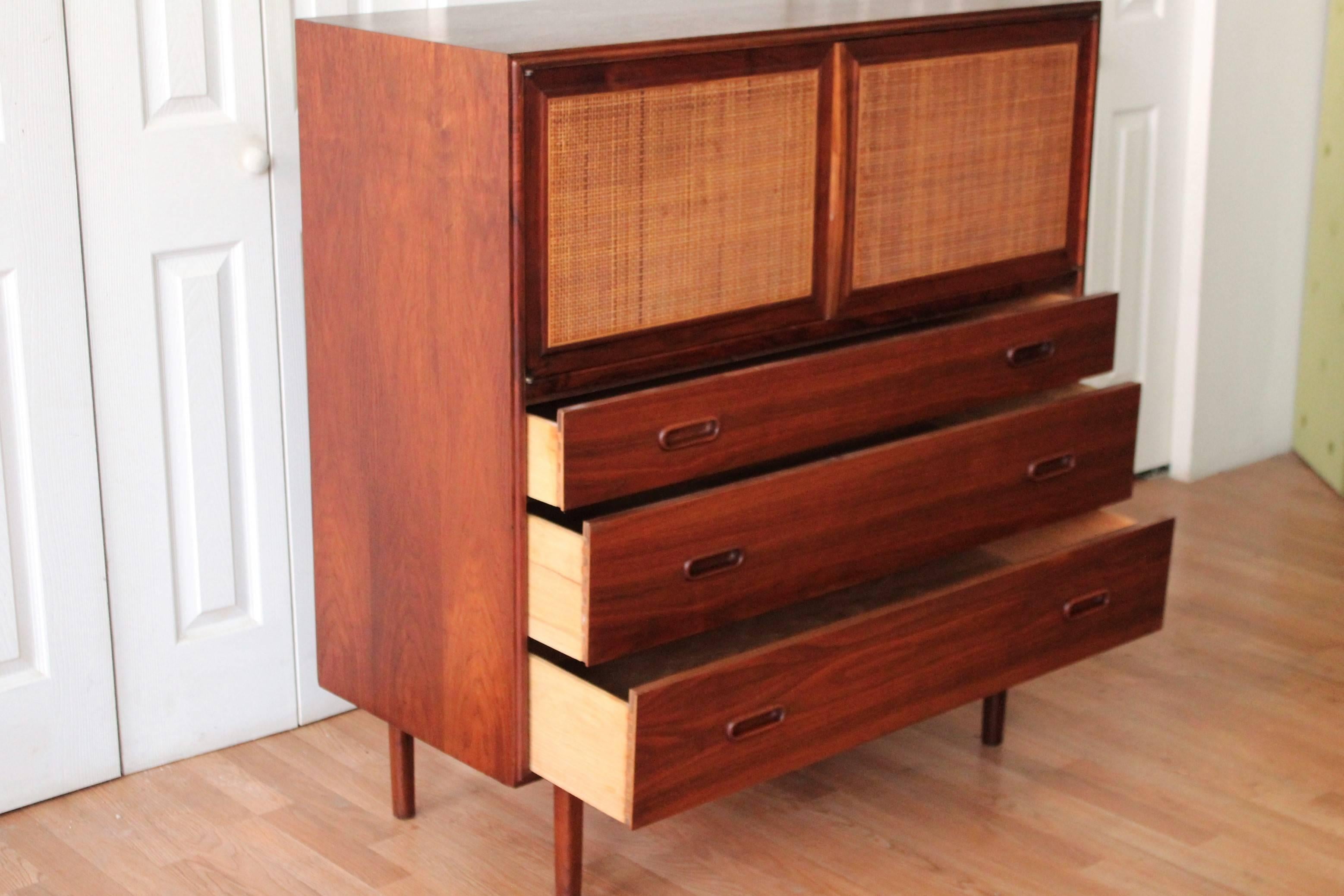 Original finish walnut highboy designed by Jack Cartwright for Founders. Ladies and gentlemen, it just doesn't get any better than this! 

Walnut Mid-Century Modern highboy with three graduating drawers, two cane front doors that open at chest