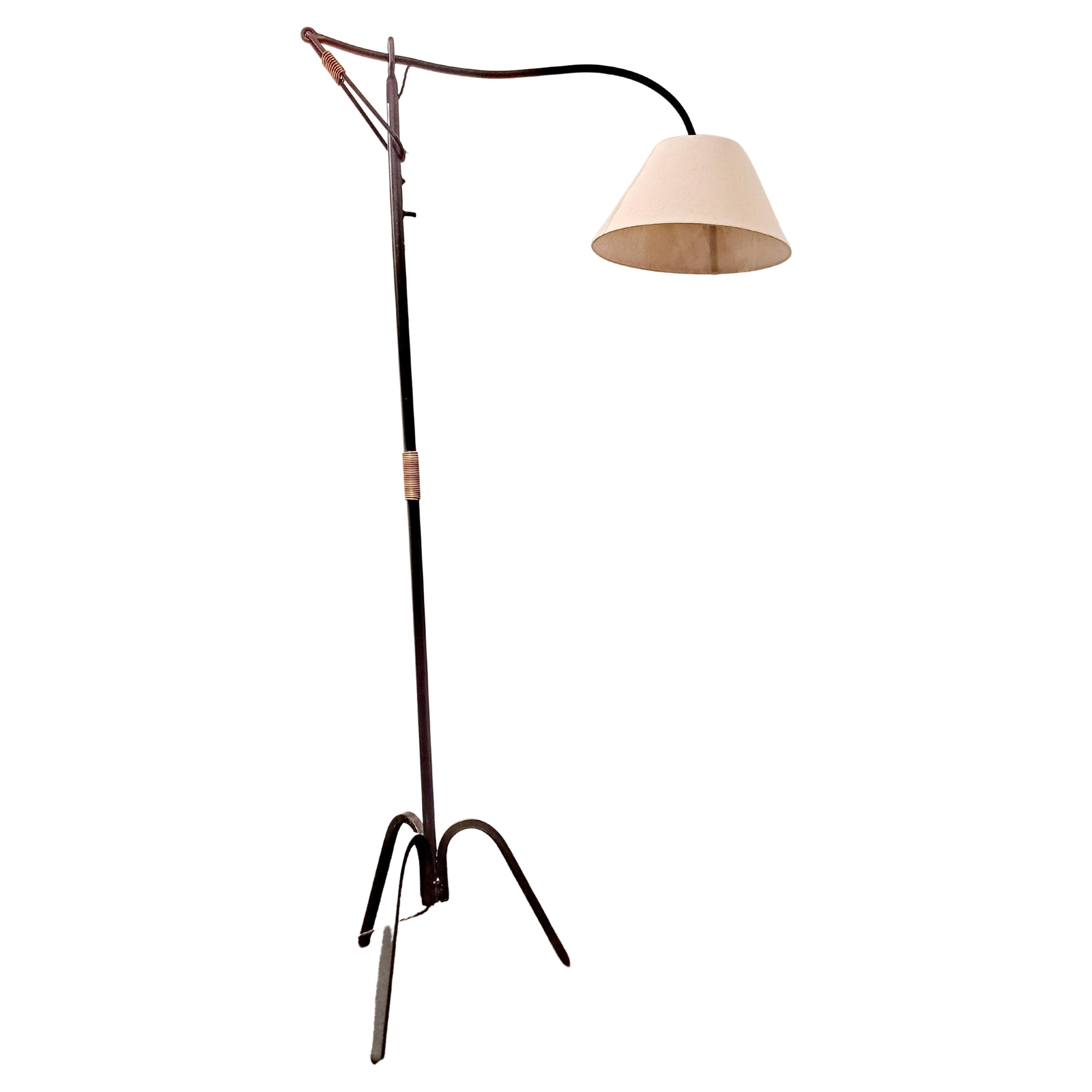 Mid-Century Modern vintage adjustable floor lamp from black iron and brass details attributed to Jacques Adnet 1950s France. Solid heavy iron with a lovely brass-wrapped accent around the stem. Newly rewired standards. In good condition with patina