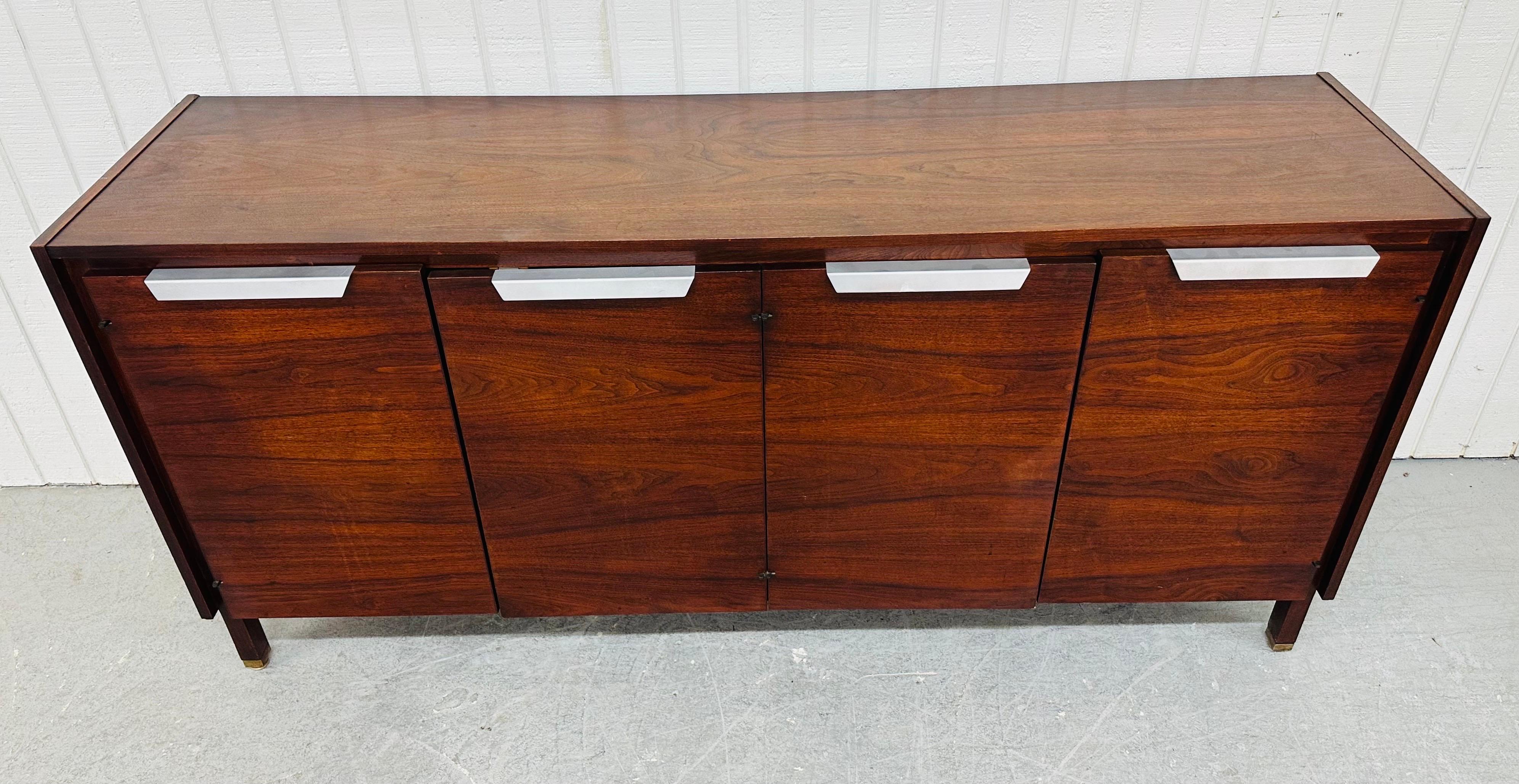 Questo annuncio si riferisce a una credenza in legno di palissandro in stile Jens Risom, di epoca moderna. Il design è lineare, le quattro ante si aprono per creare uno spazio di archiviazione, ogni ripiano è regolabile o rimovibile, le gambe sono