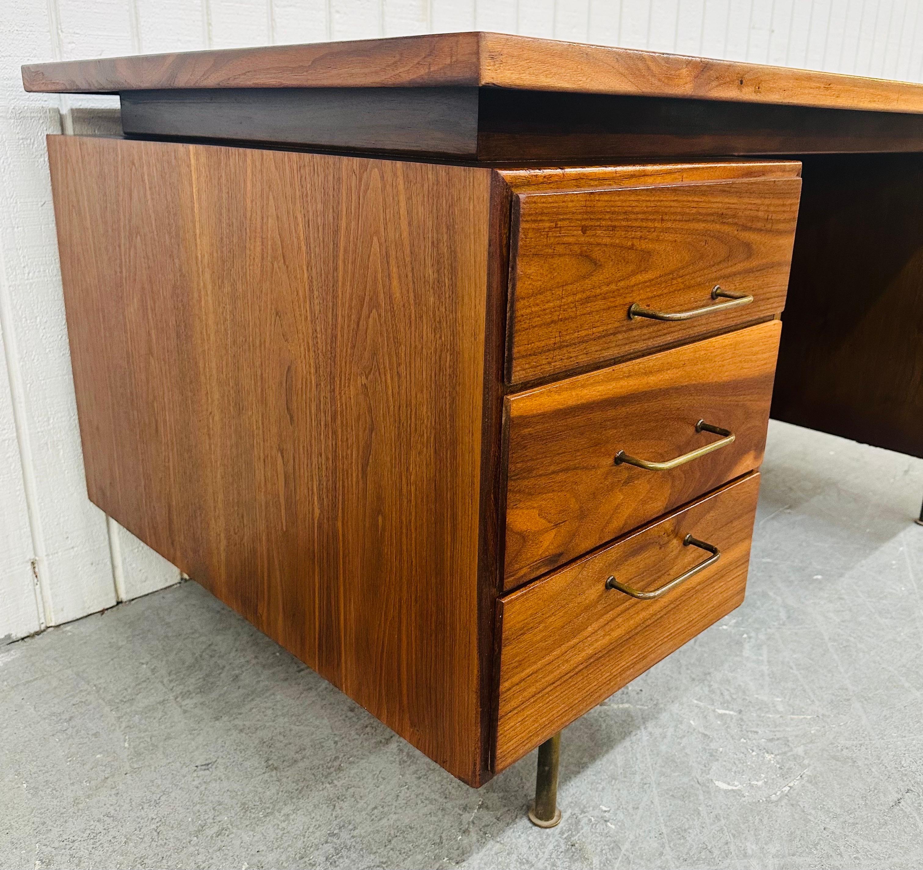 This listing is for a Mid-Century Modern Jens Risom Style Walnut Executive Desk. Featuring a straight line design, large rectangular walnut top, five drawers with brass pulls, modern brass legs, and a beautiful finished backside. This is an