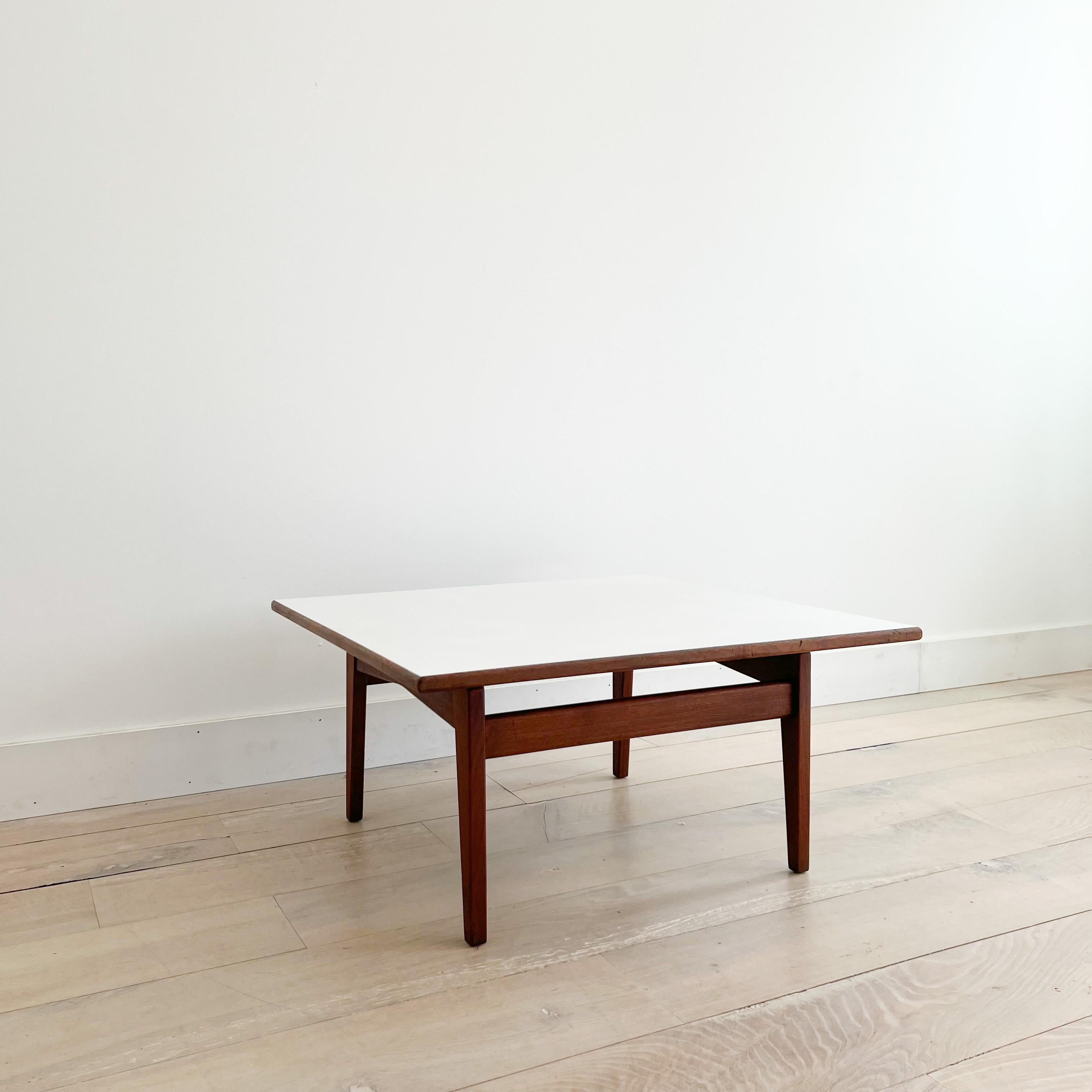 Mid-Century Modern walnut coffee table with white Formica top designed by Jens Risom. Some light scuffing/scratching from age appropriate wear.
       