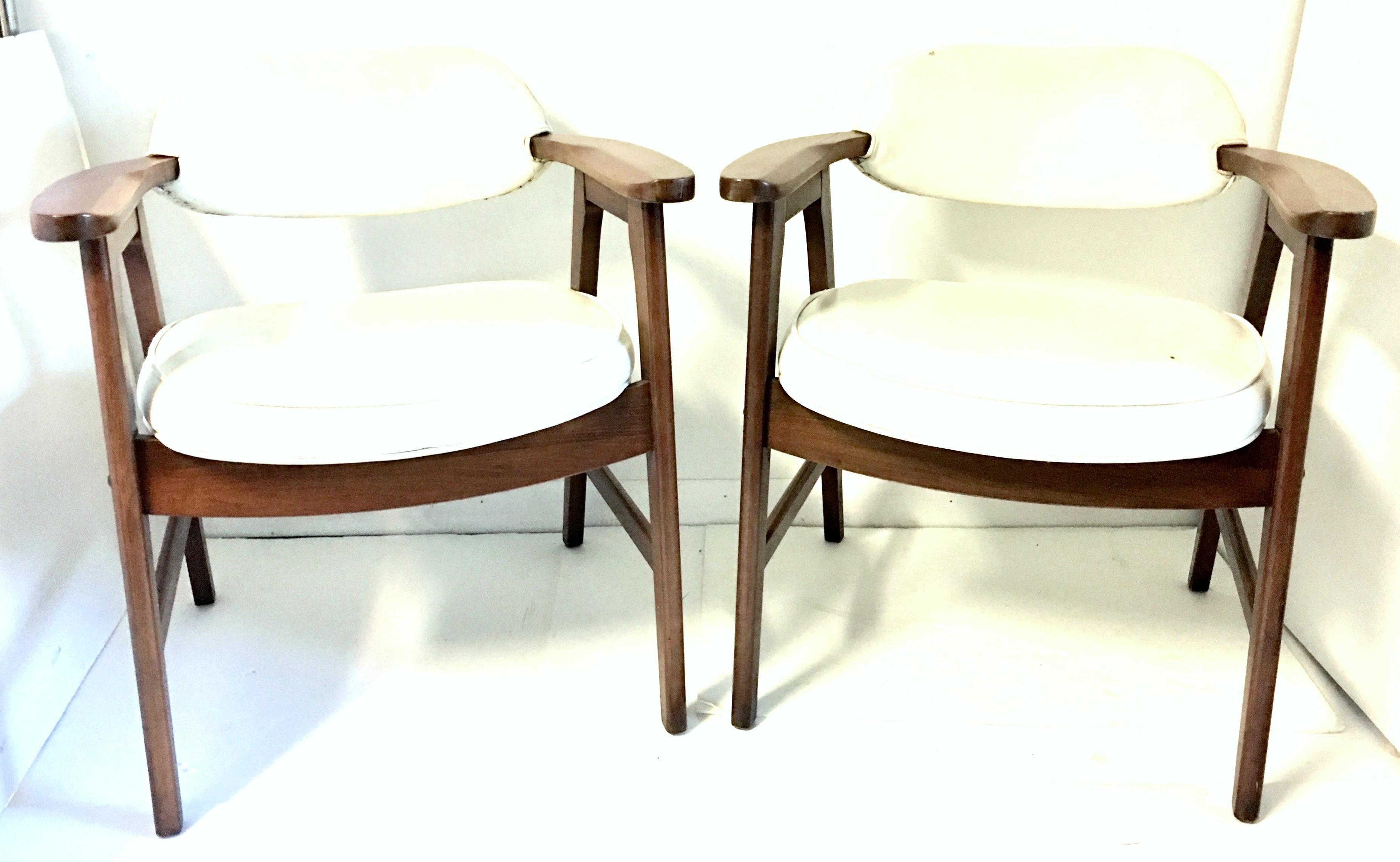 Quintessential Mid-Century Modern pair of two Jerry Johnson style, walnut upholstered armchairs. Fantastic satin finish using walnut rivet detail construction. Fabric is white faux leather, self welt with a nail head detail on upper back.
Measures: